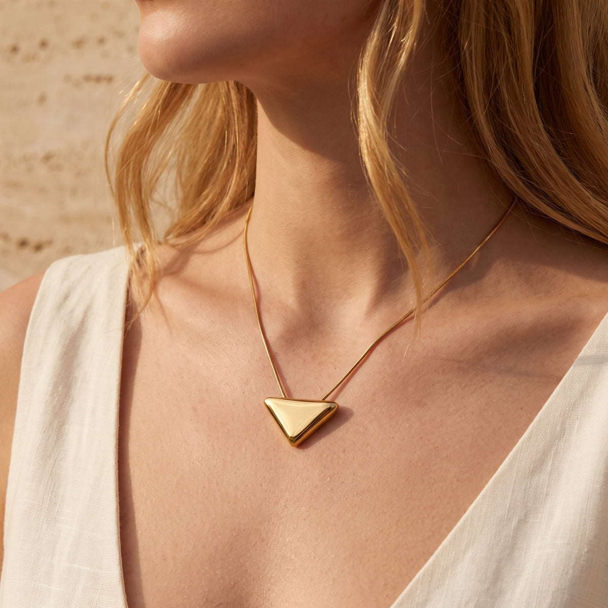 Front view of a model wearing the gold-tone inverted triangle pendant necklace.