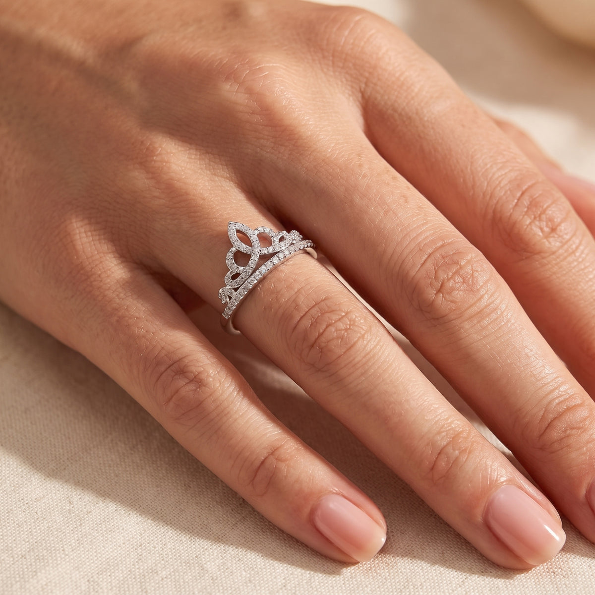 Silver tiara crown ring with cubic zirconia pave stones worn on a finger, viewed from above.