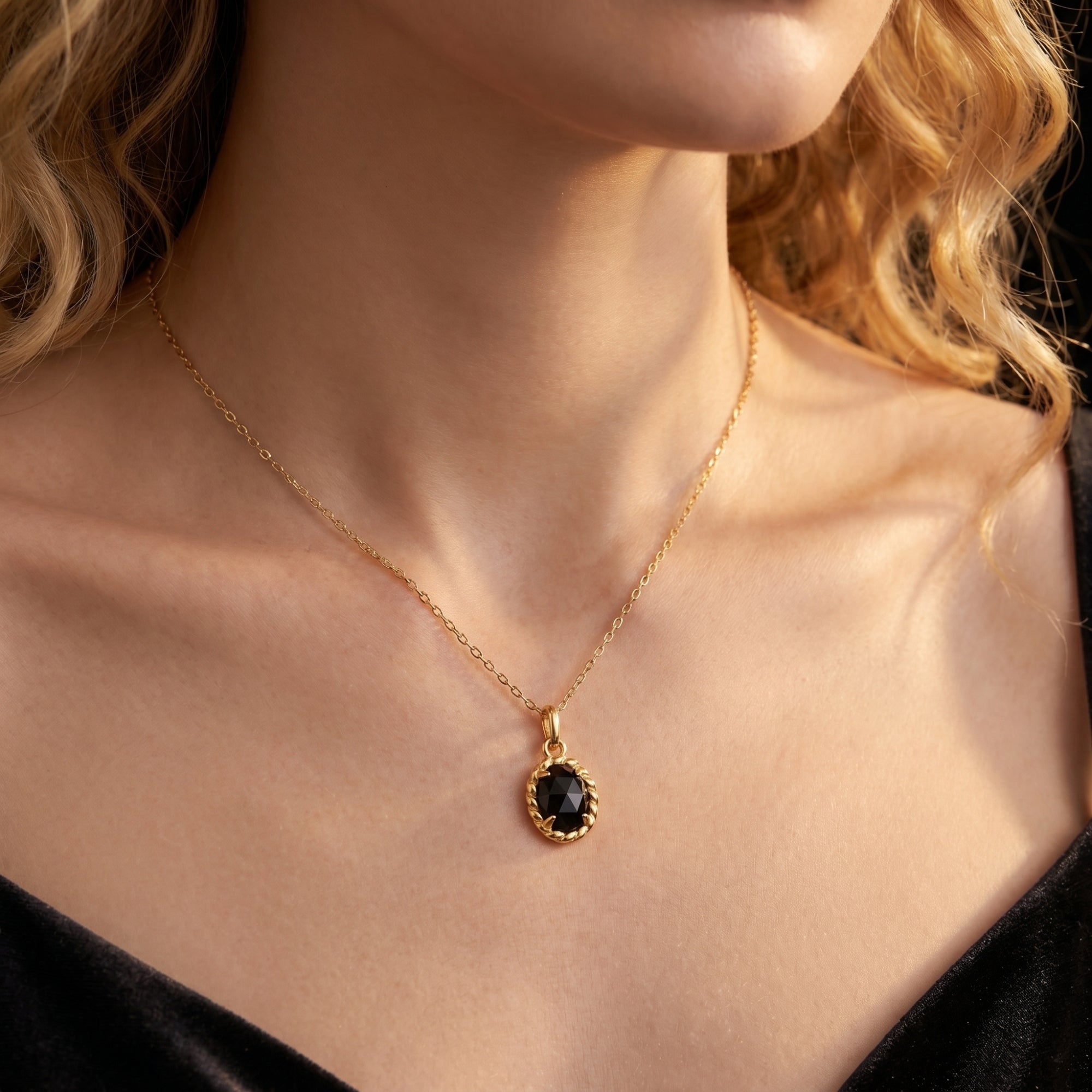 Model wearing the Raven Onyx Necklace, featuring an oval black onyx pendant on a delicate yellow gold chain.