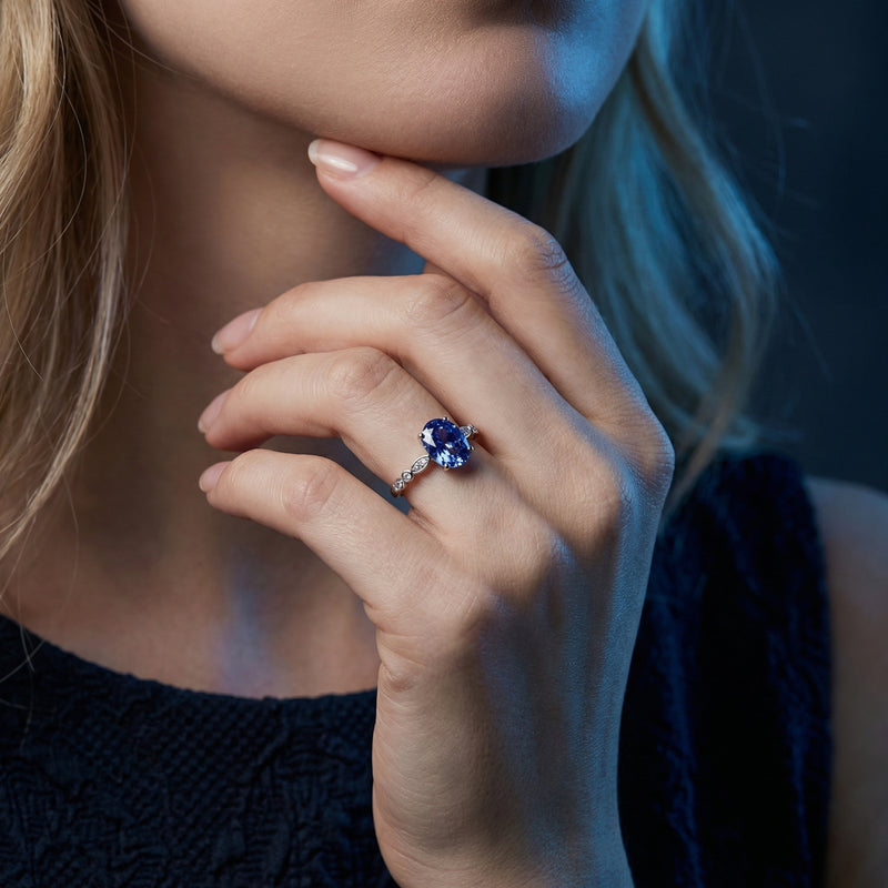 Woman wearing the oval cut tanzanite sterling silver ring on her finger, showcasing its size and color.