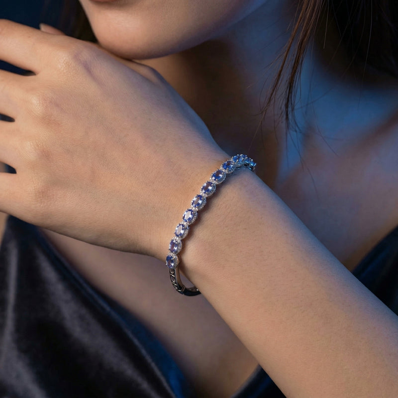 Close-up of the Alvira oval tanzanite bangle in white gold worn on a woman's wrist.