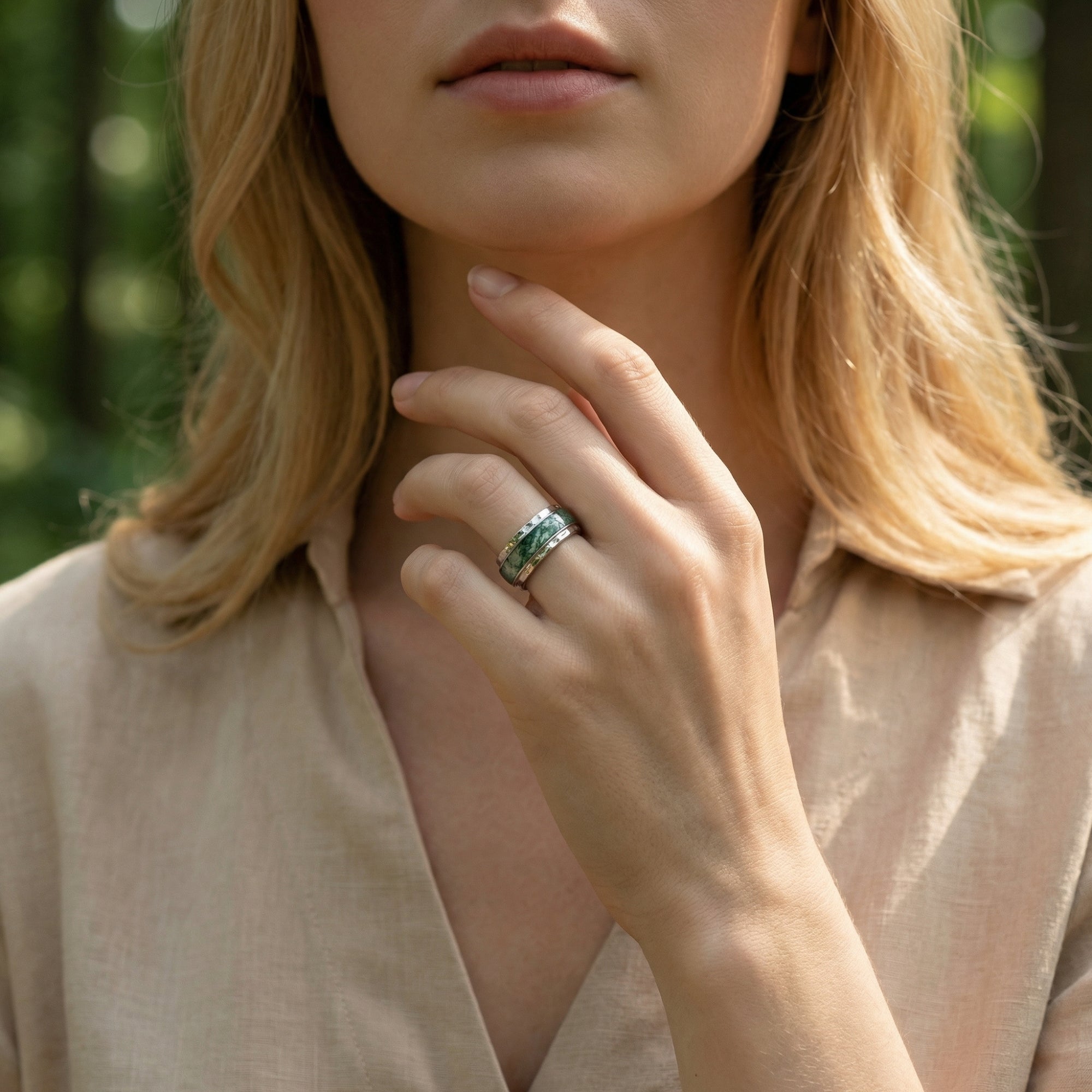Woman wearing the natural moss agate sterling silver inlay band ring on her finger in a natural setting.