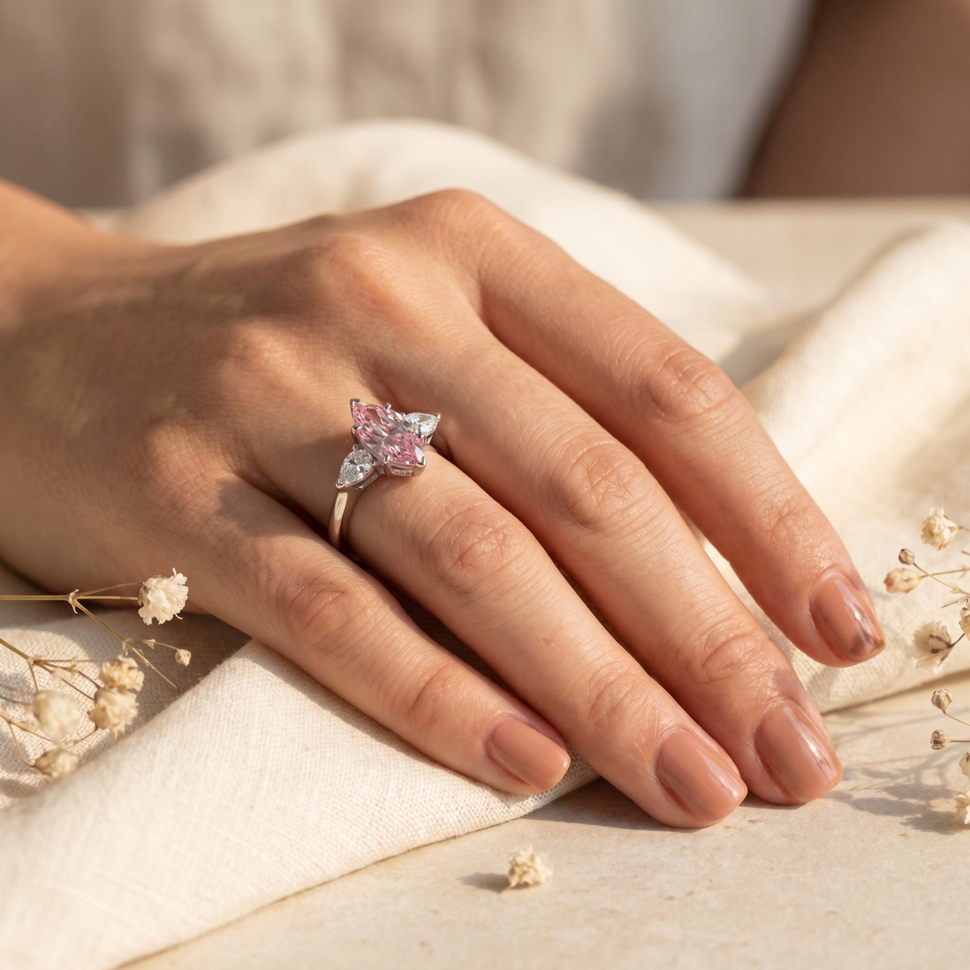 Marquise pink moissanite silver ring worn on a woman's hand against a soft fabric background.