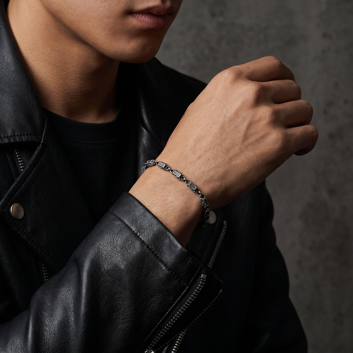 Man wearing the silver geometric link bracelet with a black leather jacket.