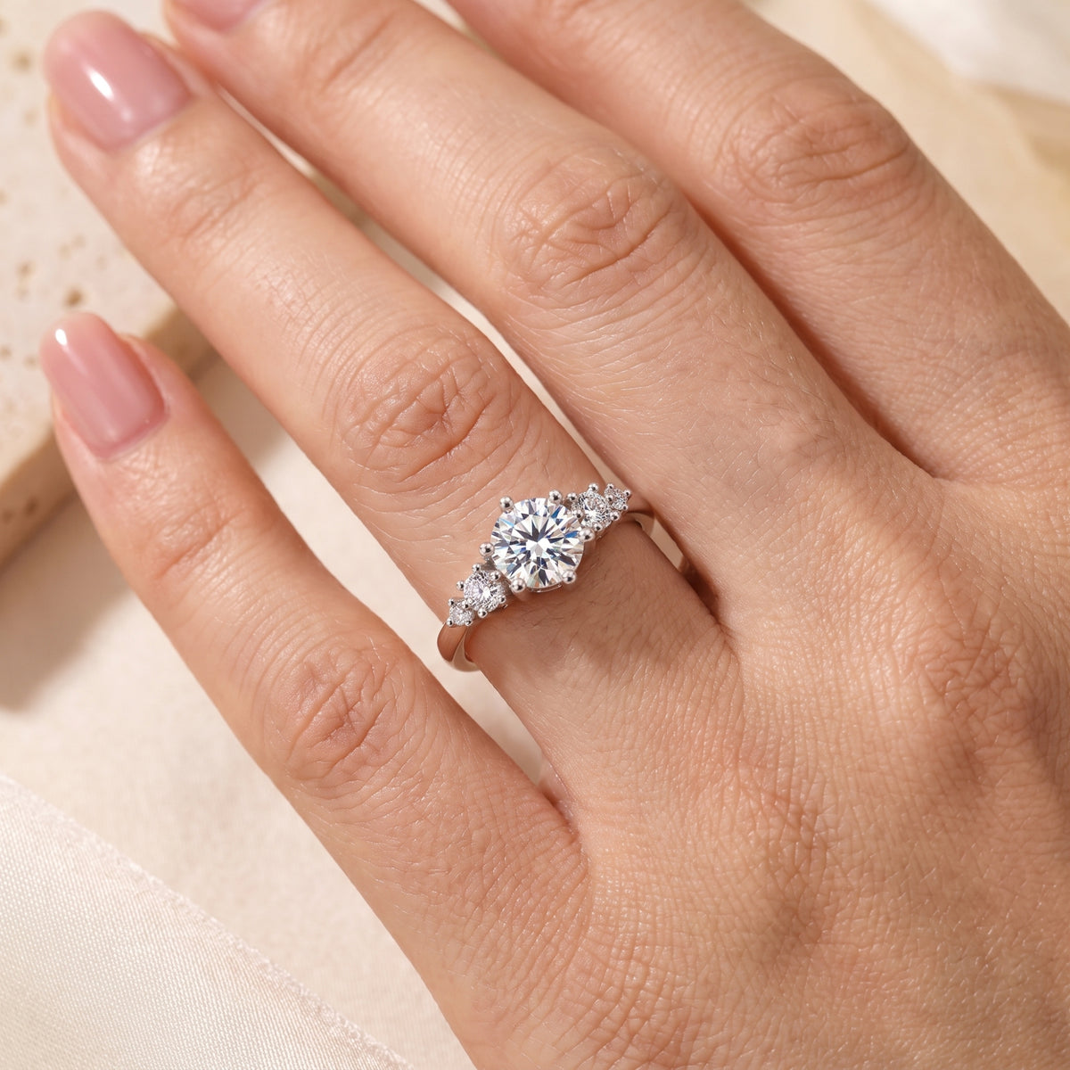 Close-up of the silver ring with a round center stone and clustered side accents worn on a hand