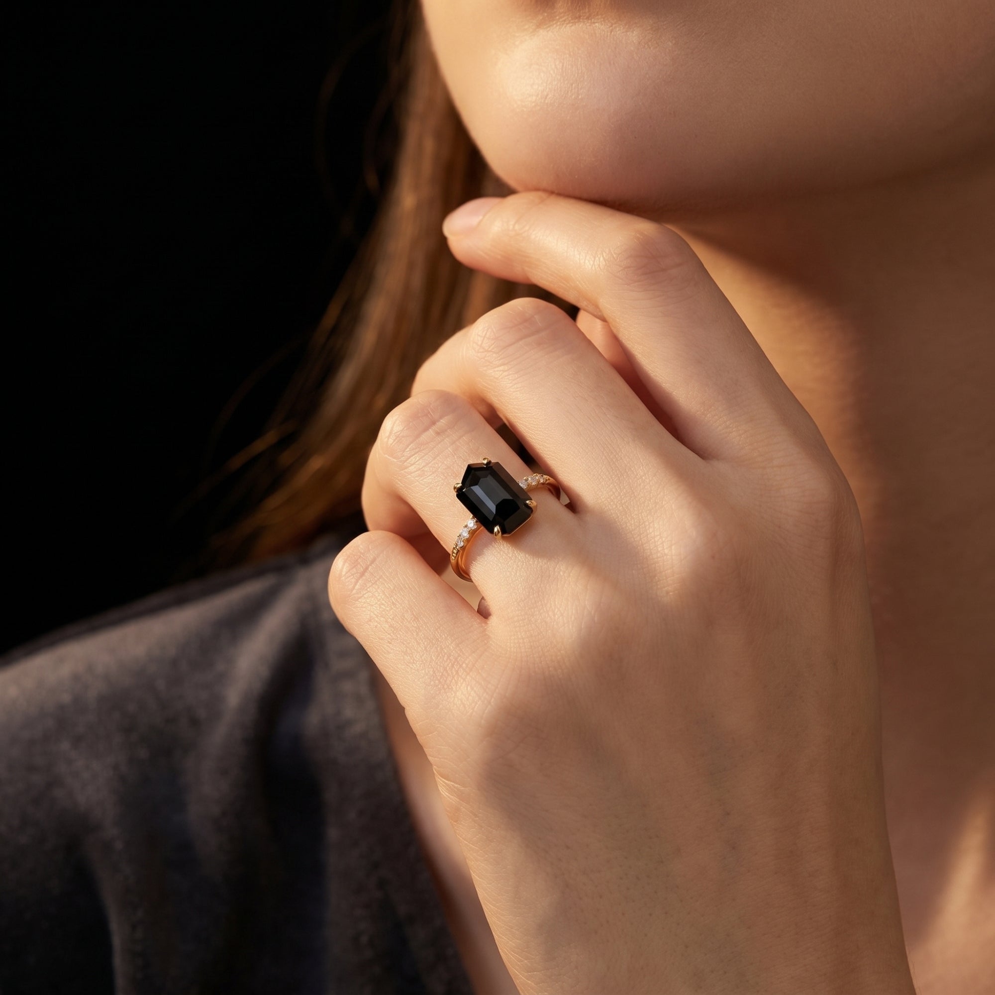 Woman wearing the Noctura natural onyx statement ring in 18K gold vermeil with zircon accents on her finger.