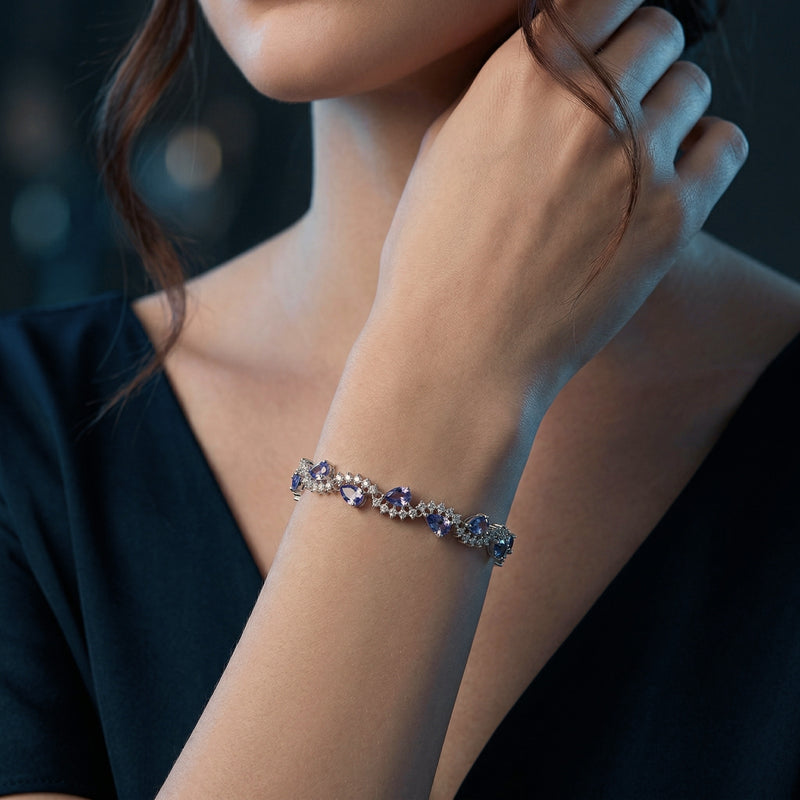 A woman wearing the pear cut tanzanite and silver tennis bracelet on her wrist.