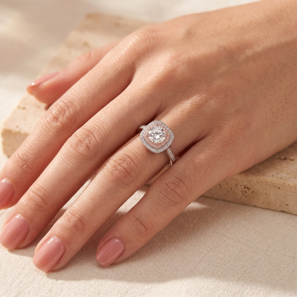 Hand wearing the silver dual-halo ring on a ring finger, showing its clear center stone and pink inner halo.