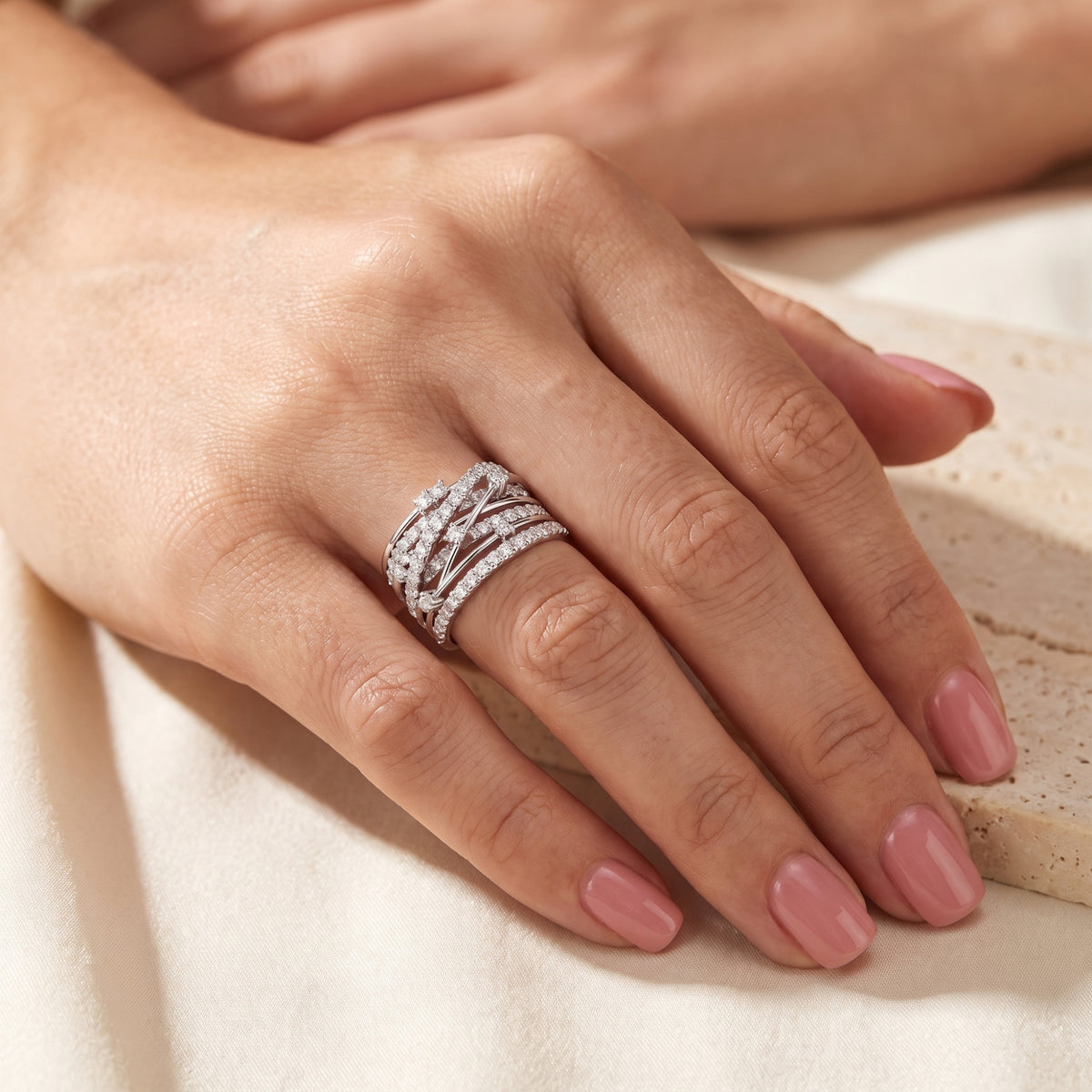 Full hand view showing the silver multi-band criss-cross ring worn on the ring finger.