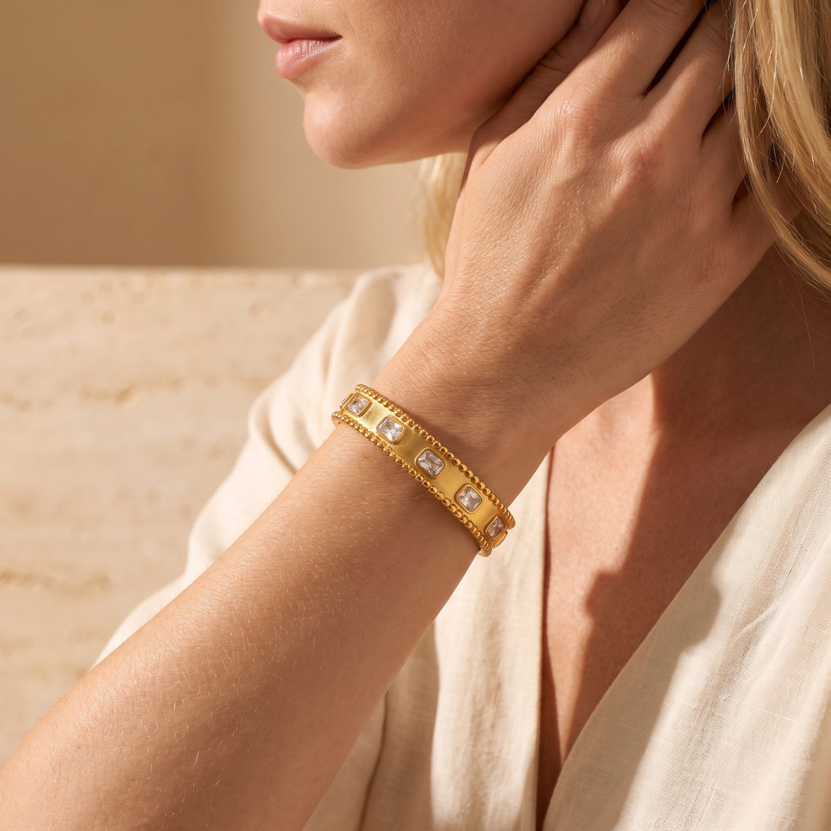 Close-up of a model wearing the gold-tone beaded cuff bracelet with clear bezel-set stones on her wrist.