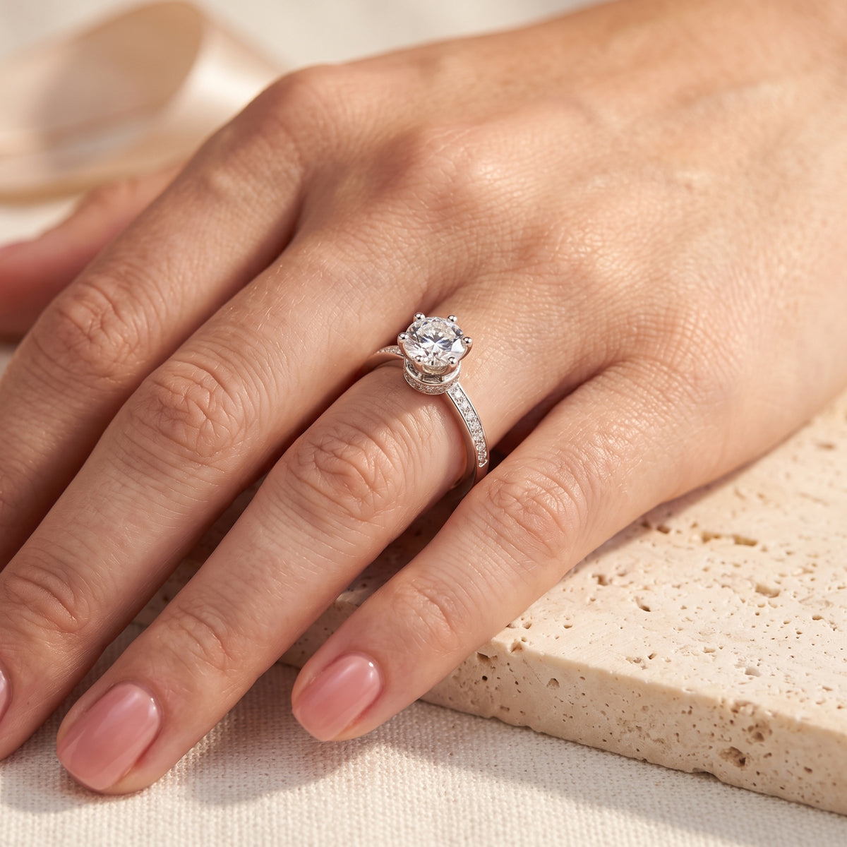 Top-down view of a hand wearing the silver crown solitaire ring with a round clear gem on a ring finger.