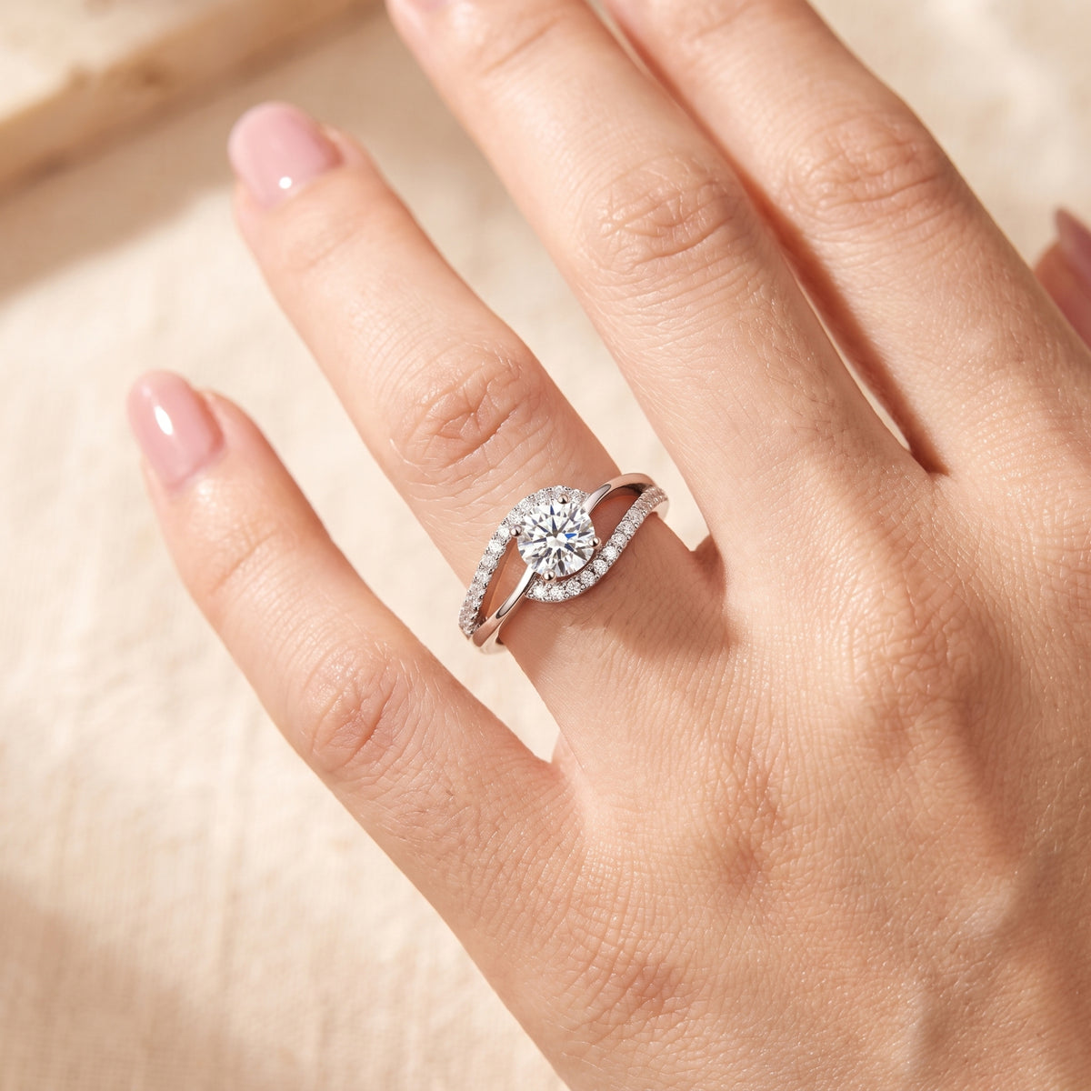 Close-up of a hand wearing the silver bypass ring with a round clear center stone and pavé accents.