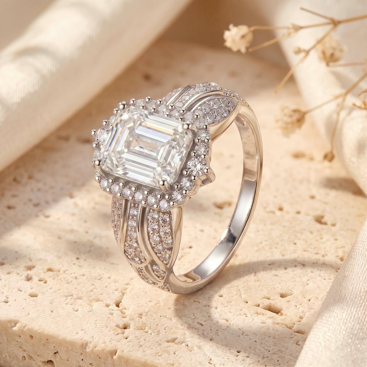 Three-quarter view of the silver ring showcasing the emerald-cut center stone and decorative split band.