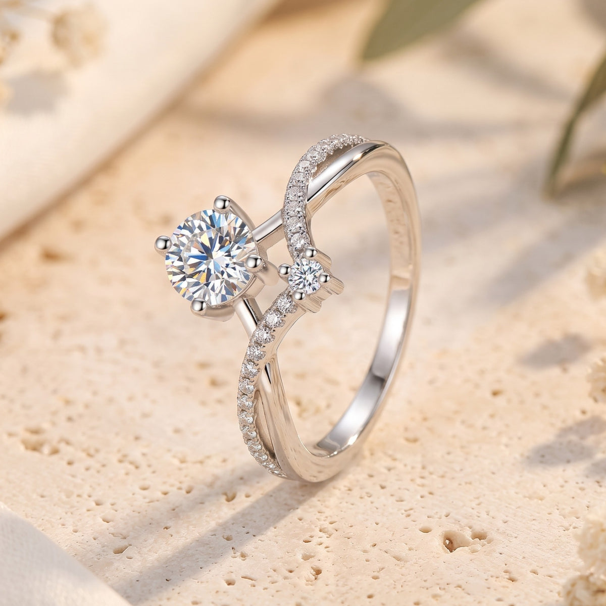 Angled close-up of the silver ring, highlighting the prong-set round stone and crossover pavé chevron band.