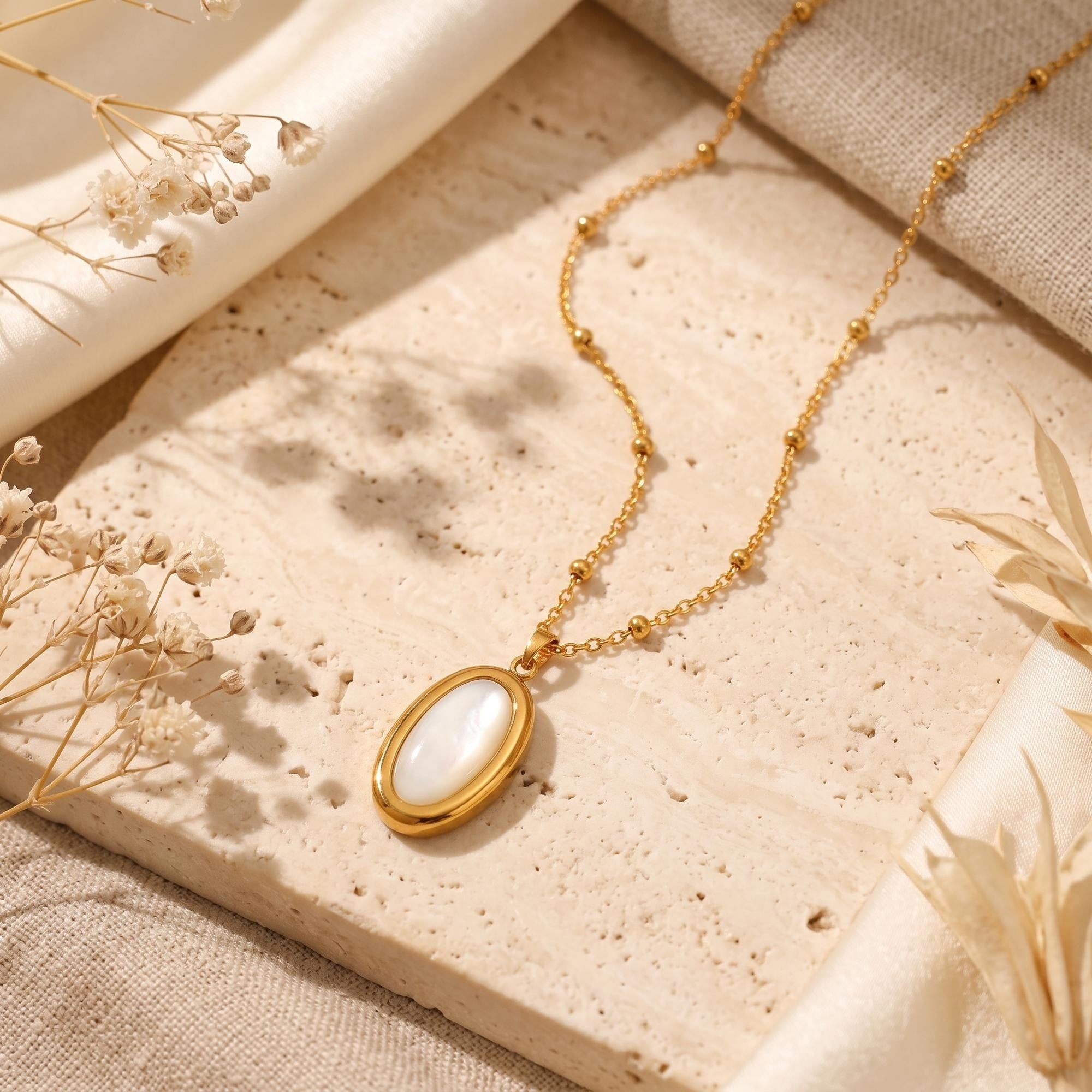 Close-up of oval mother of pearl pendant in gold frame.
