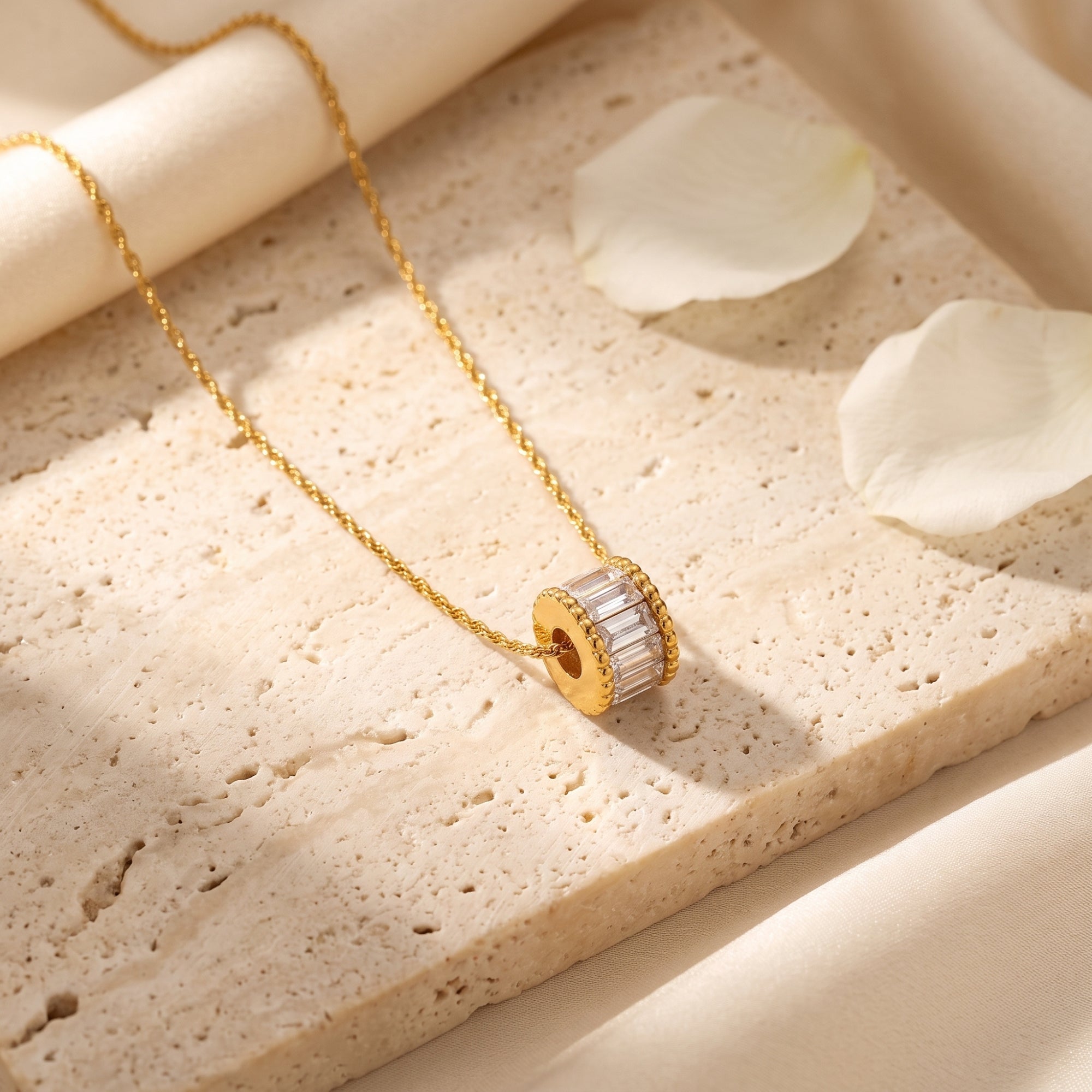 Close-up of a gold cylindrical pendant featuring baguette-cut simulated diamonds on a textured stone.