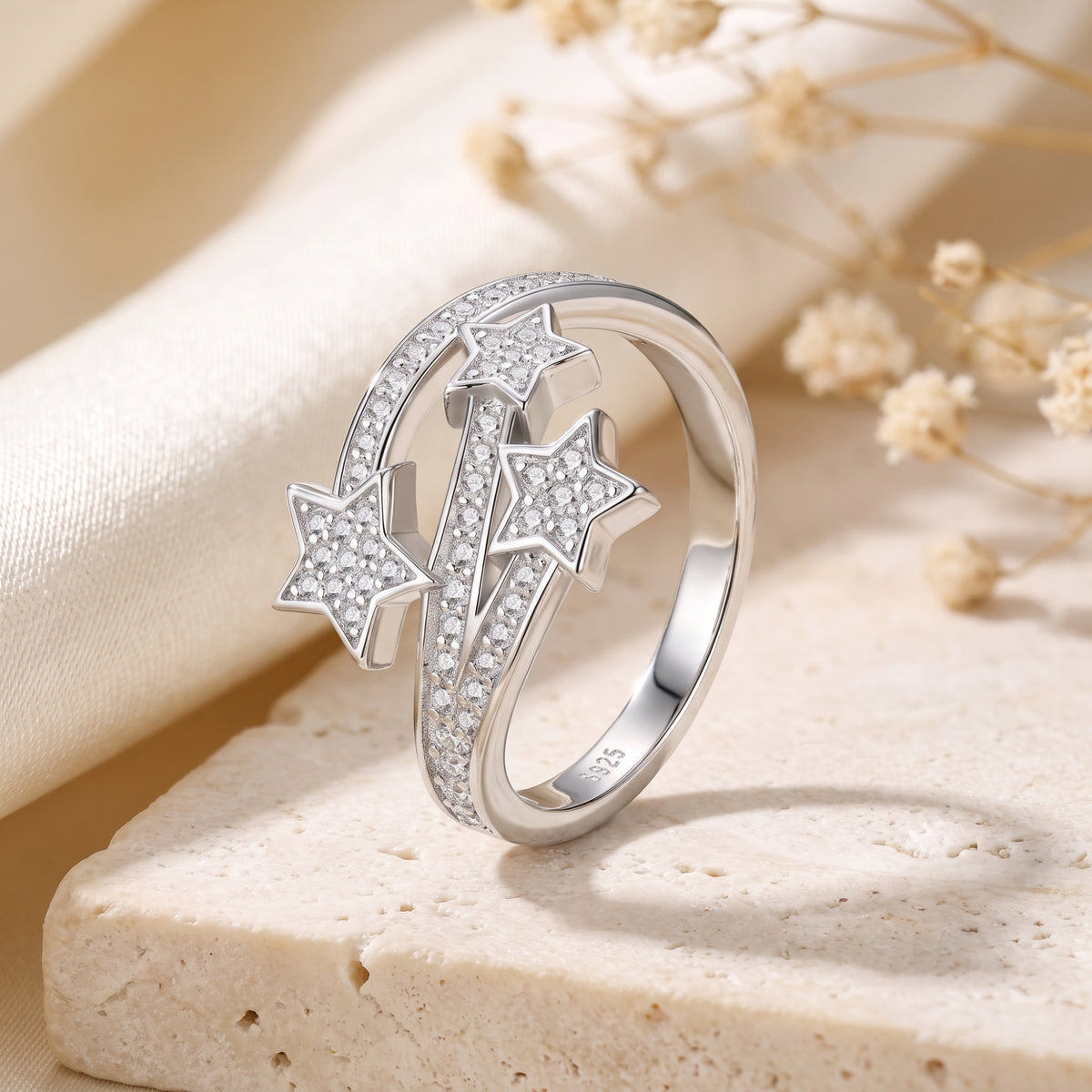 Upright view of the silver bypass ring showing three pave-set stars and curved bands.