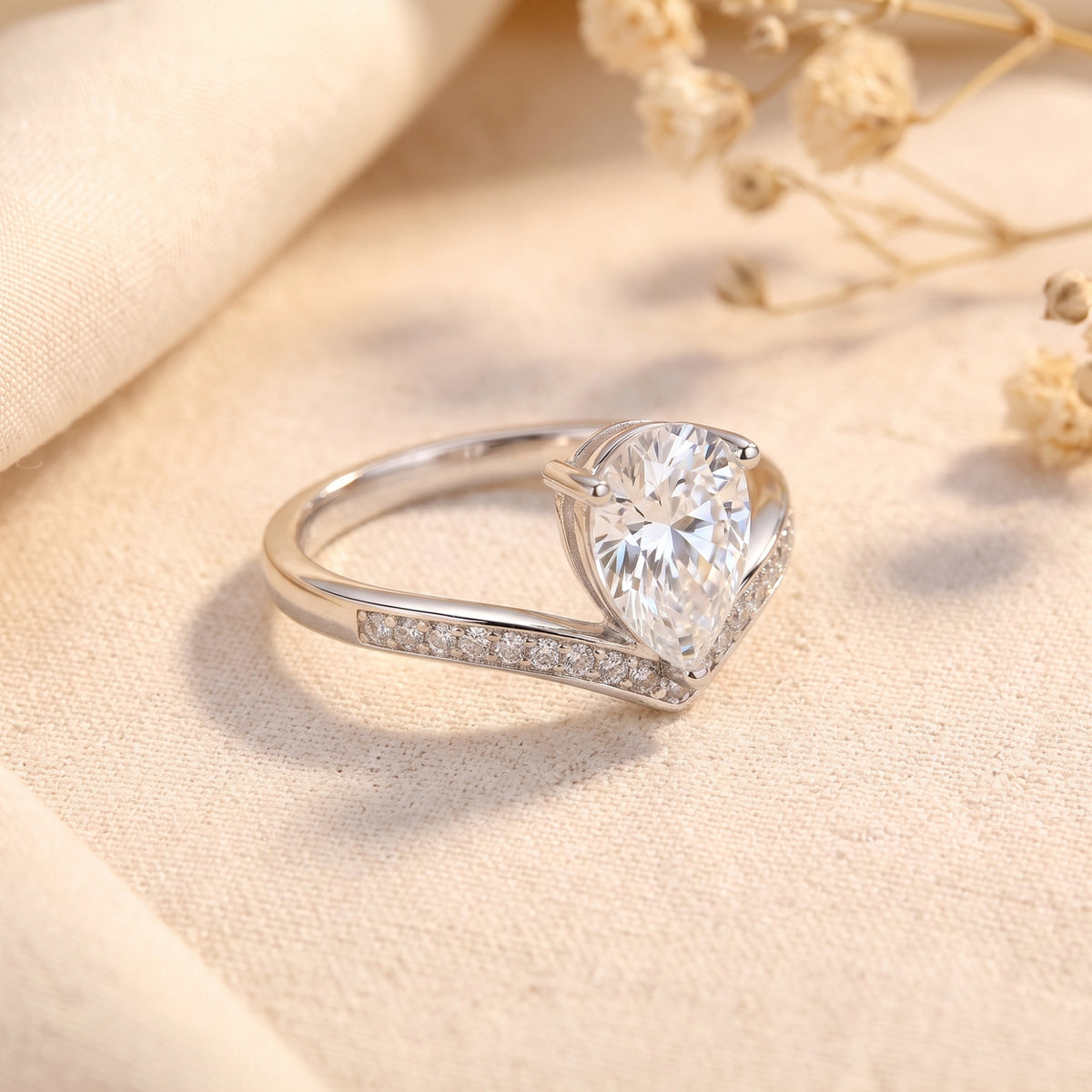 Angled side view of the silver chevron ring, showing the raised pear-shaped center stone setting and pave accents.