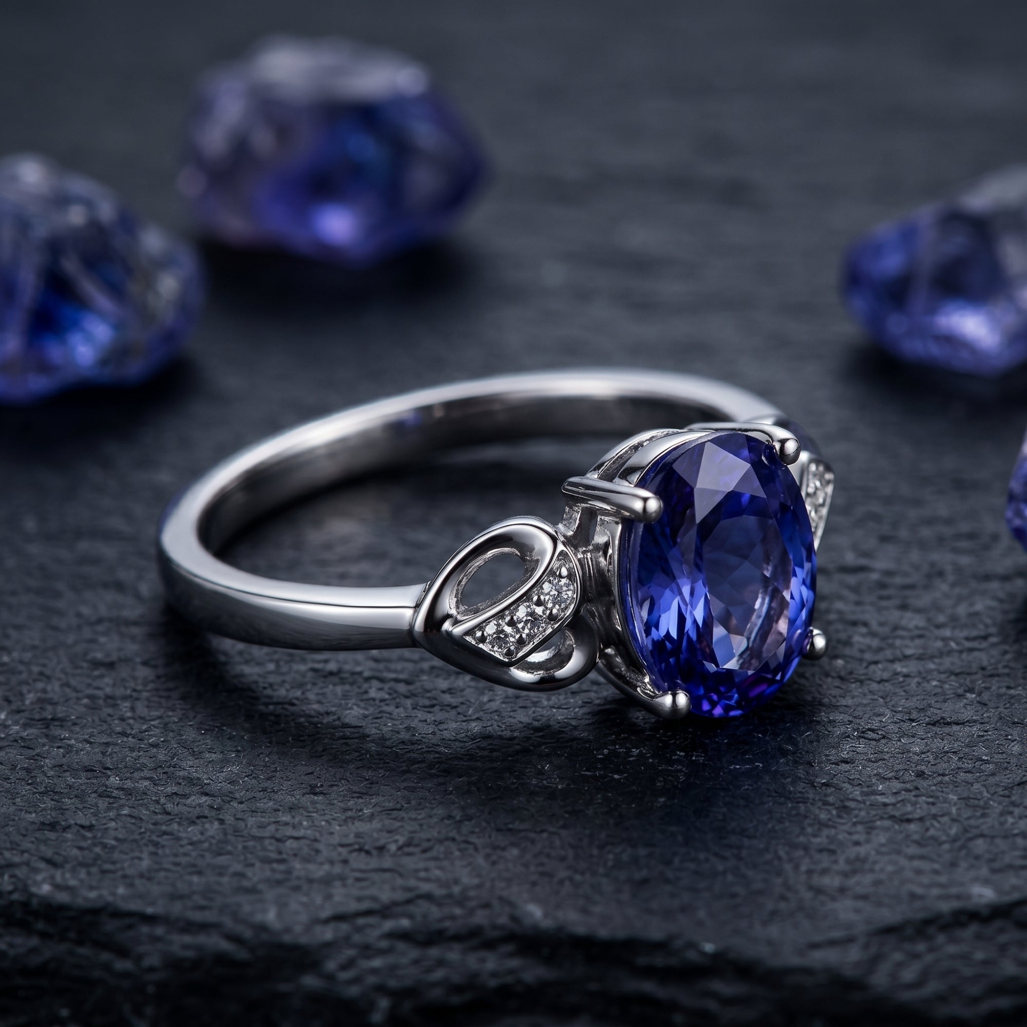 Close-up side view of the oval tanzanite and diamond-accented 18K white gold ring on a dark surface.
