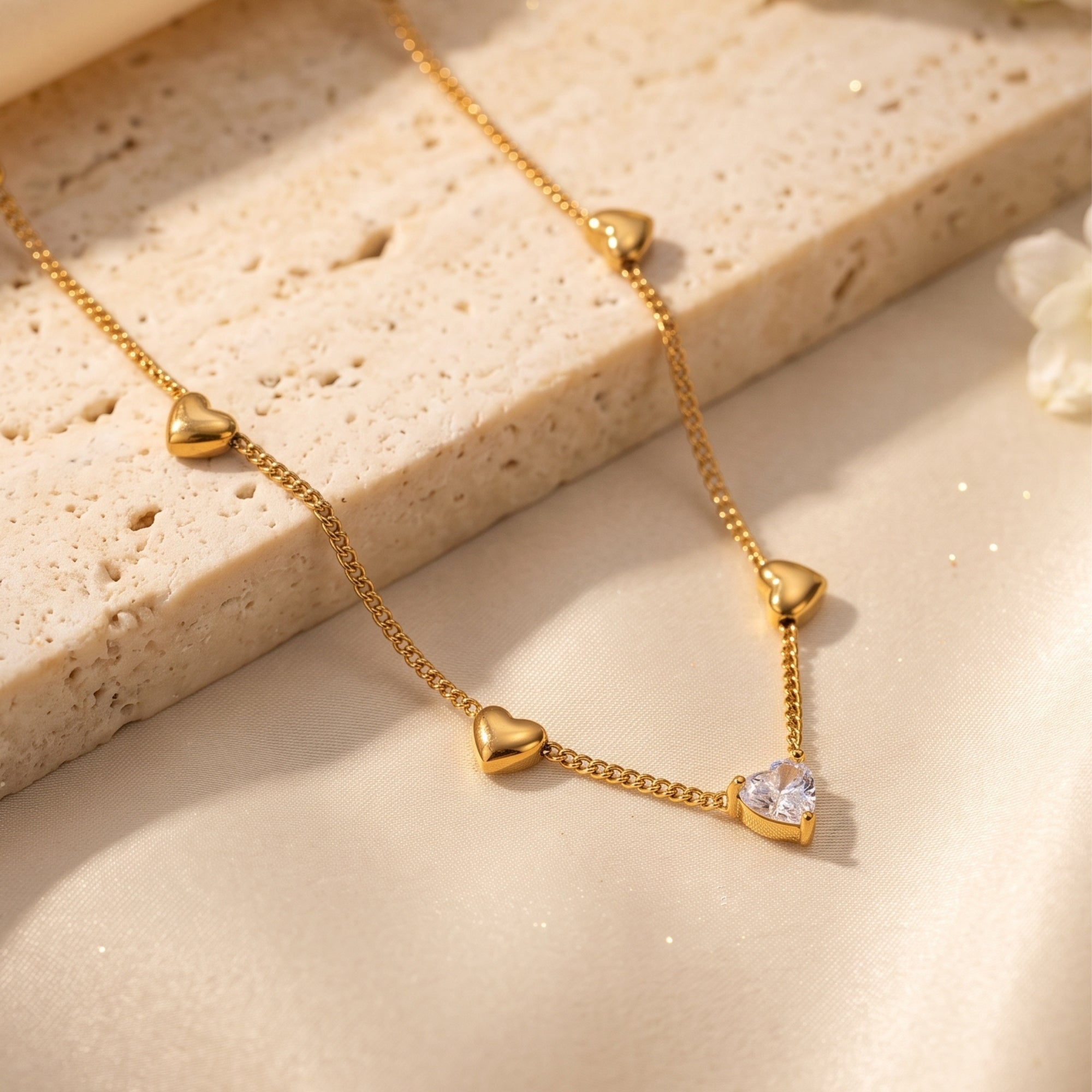 Close-up of the 18K gold heart necklace and heart-cut simulated diamond pendant on a textured stone surface.