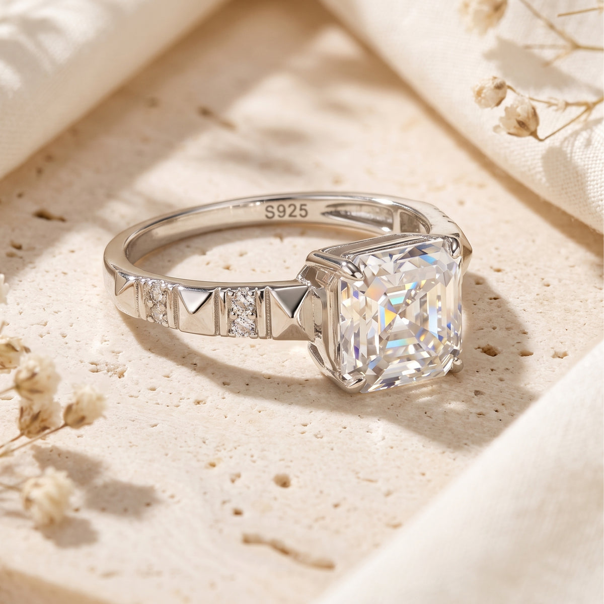 Side-angled close-up of the silver ring, highlighting the raised square center stone and textured studded band.