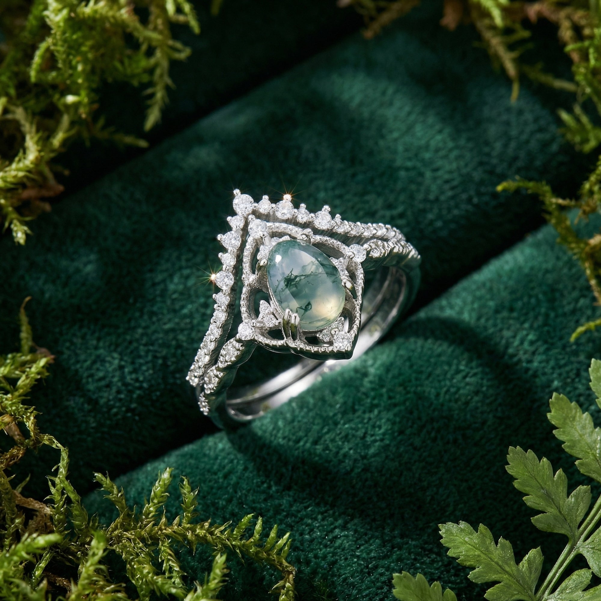 Macro shot of the diamond encrusted oval moss agate ring set in S925 sterling silver resting on green velvet.