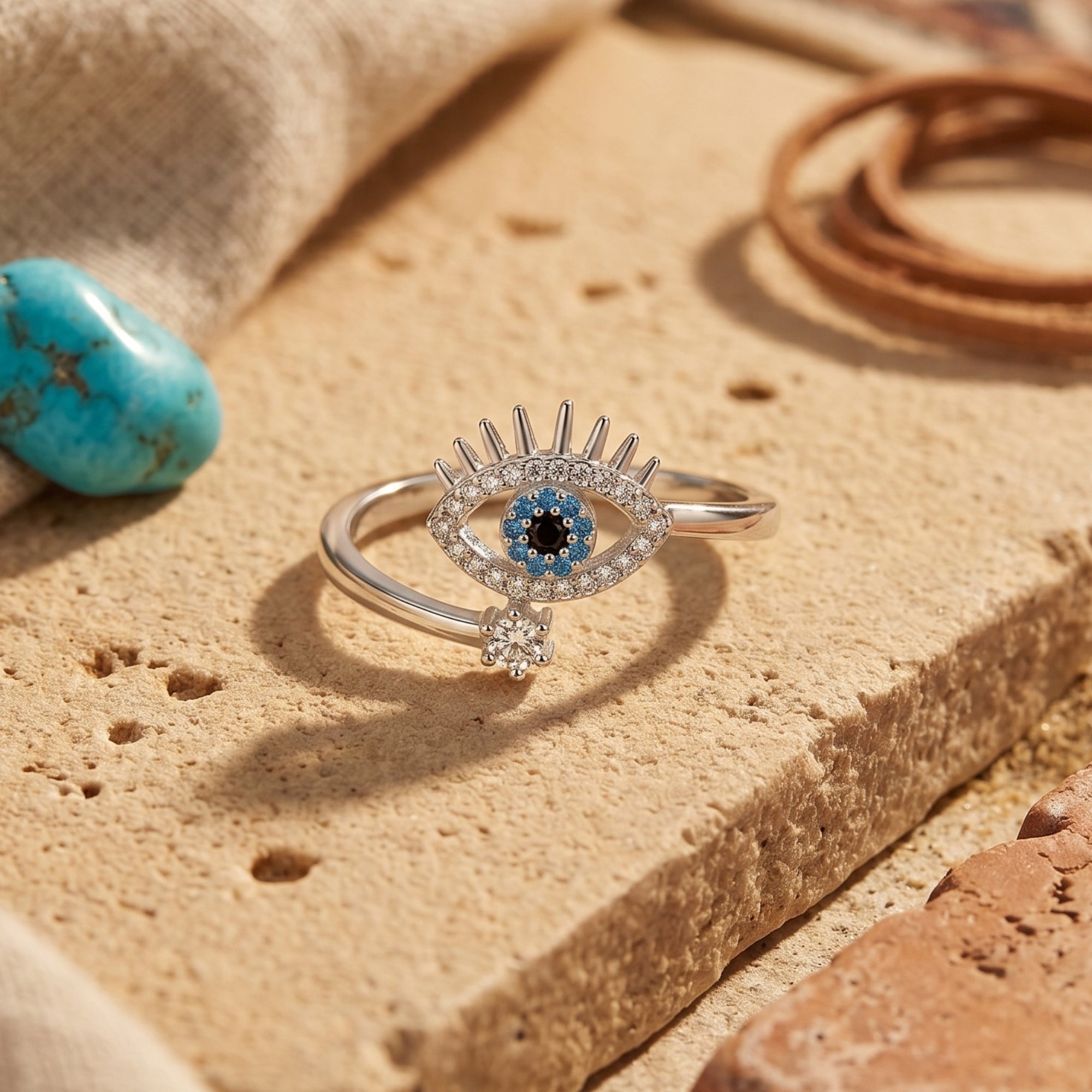 Macro view of the silver Amaya ring's turquoise evil eye motif and adjustable band on a textured stone.
