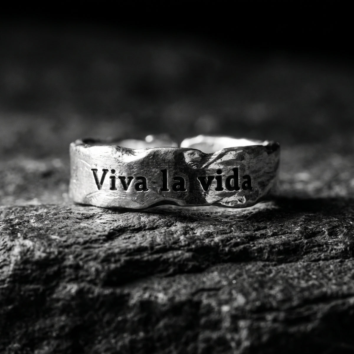 Front view of the silver hammered ring showing its dark Viva la vida inscription on textured stone.
