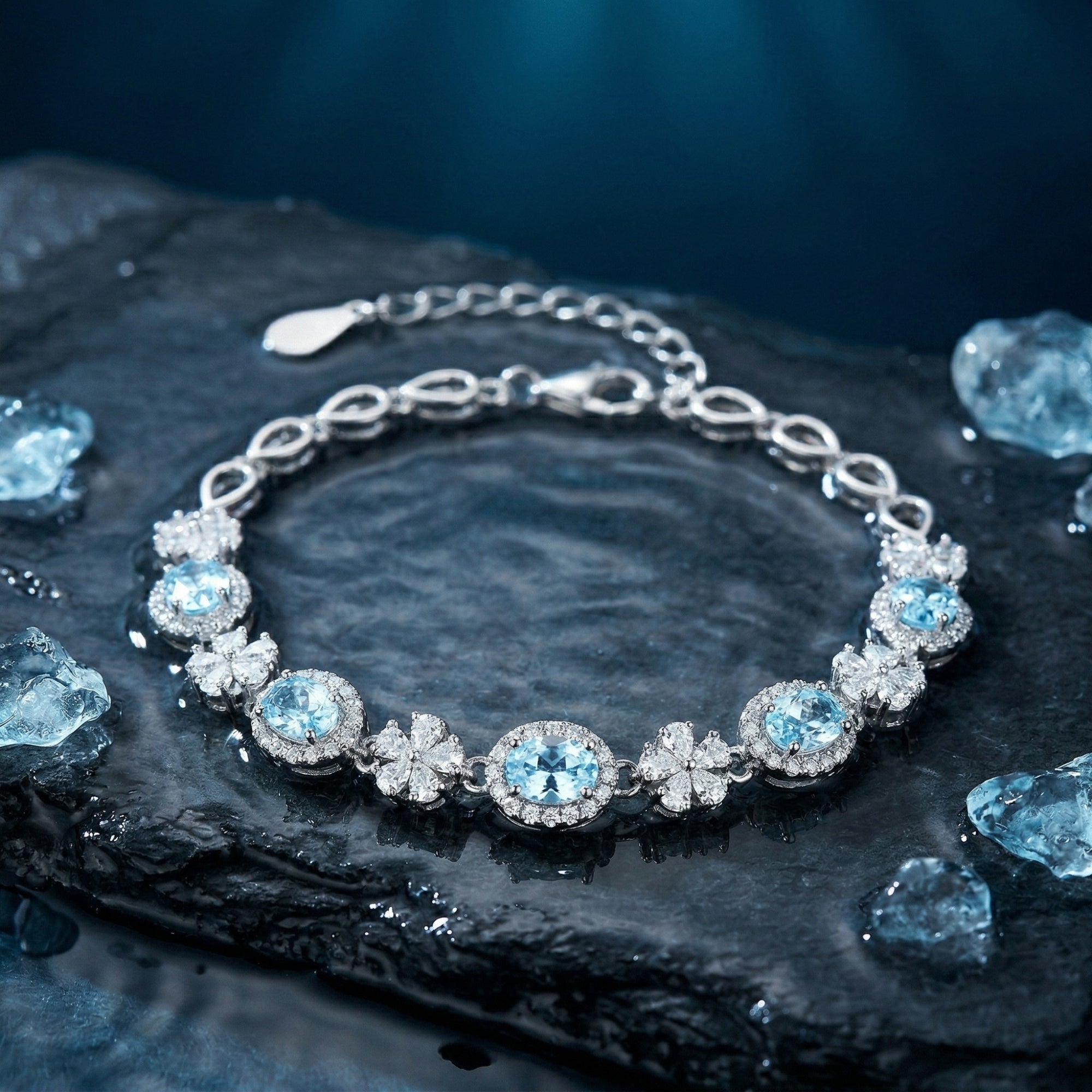 Macro view of oval cut aquamarine stones and floral accents in a white gold station bracelet.