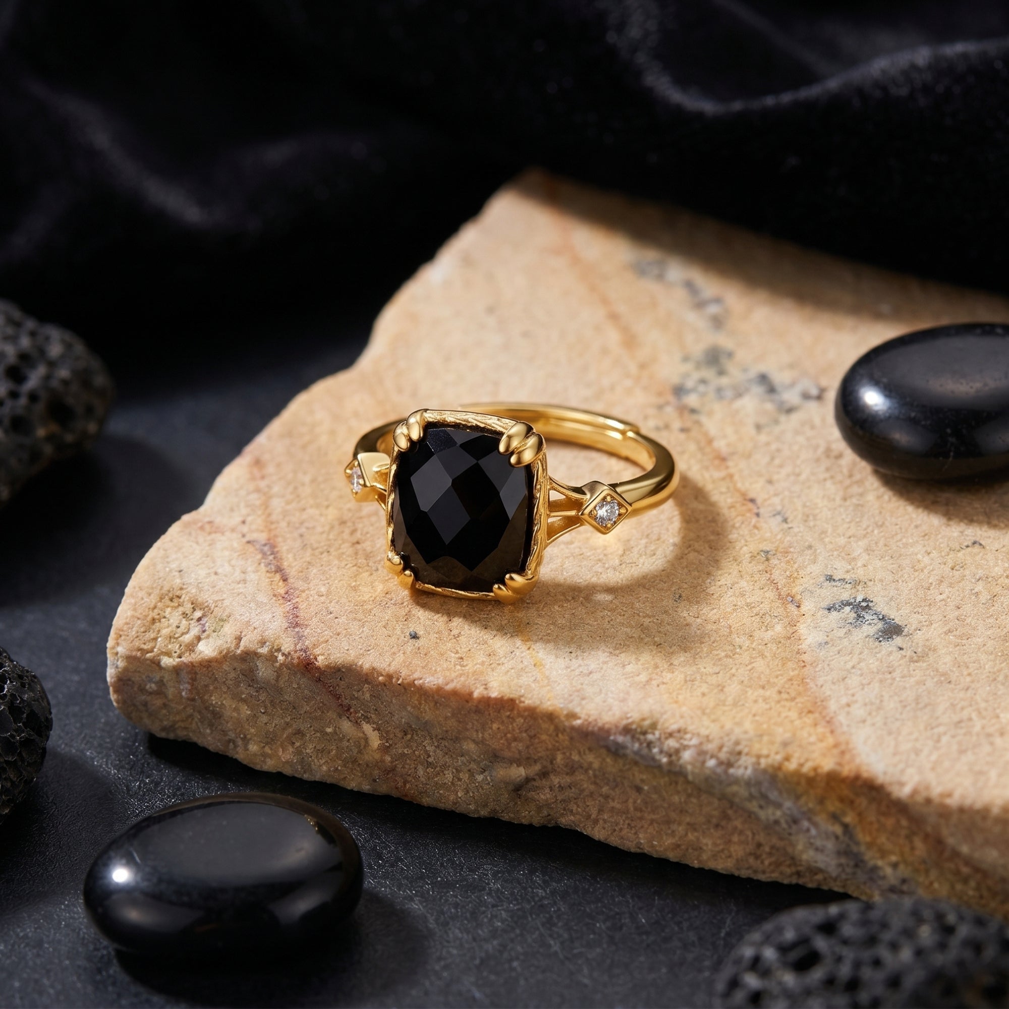 Faceted cushion-cut natural black onyx ring in 18K gold plating shown from a front angle on a stone surface.