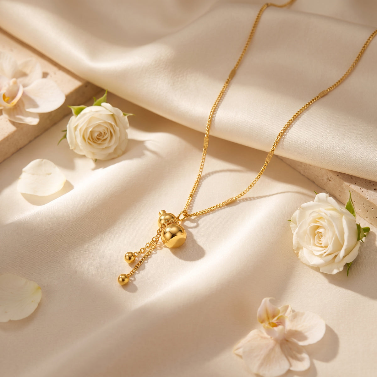 Flat-lay view of the gold-tone gourd necklace on cream satin, surrounded by white roses and petals.
