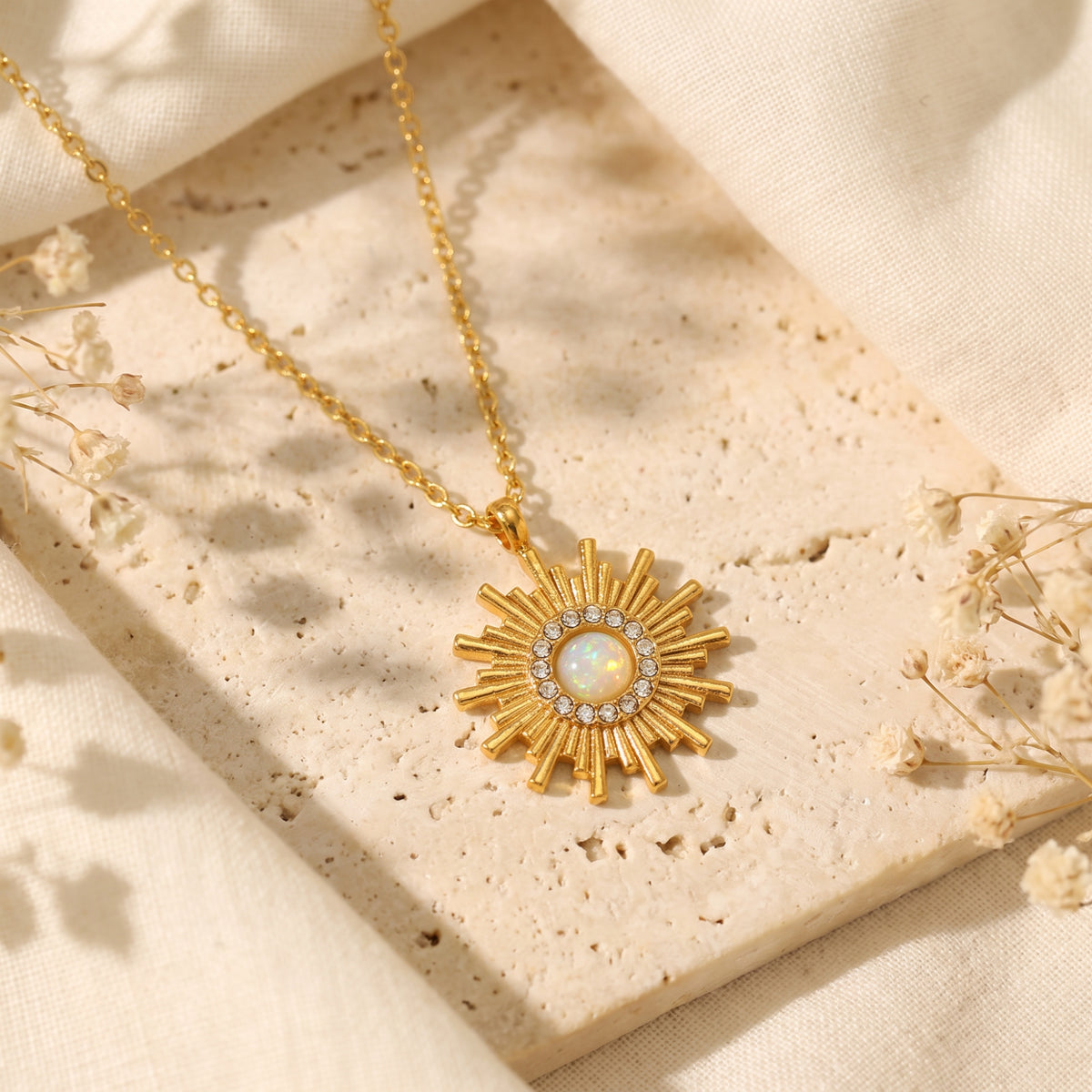 Overhead view of the gold-tone sunburst pendant with a white opal center and clear cubic zirconia halo.