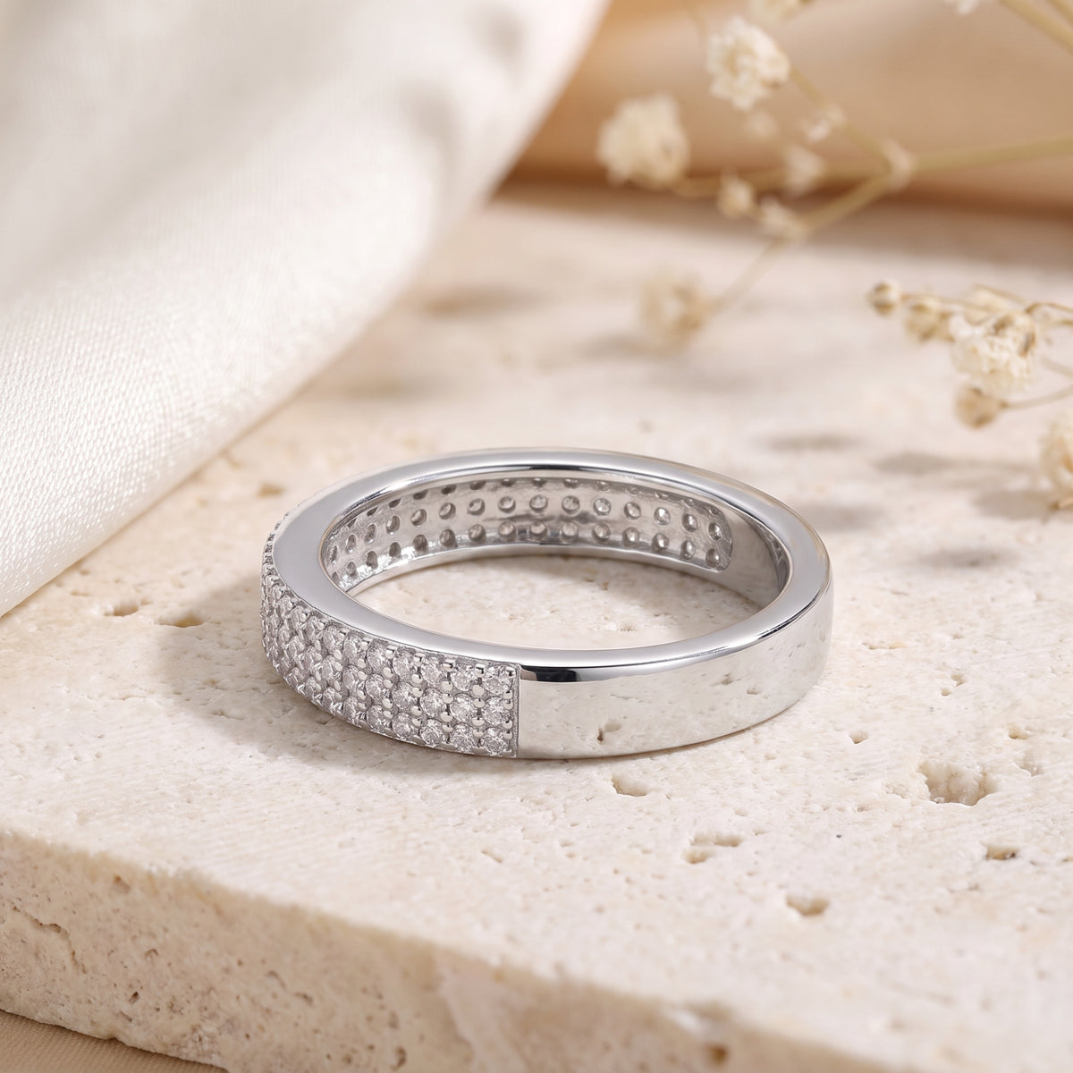 Silver band resting flat, showing three rows of pavé stones on top and openwork detailing inside.