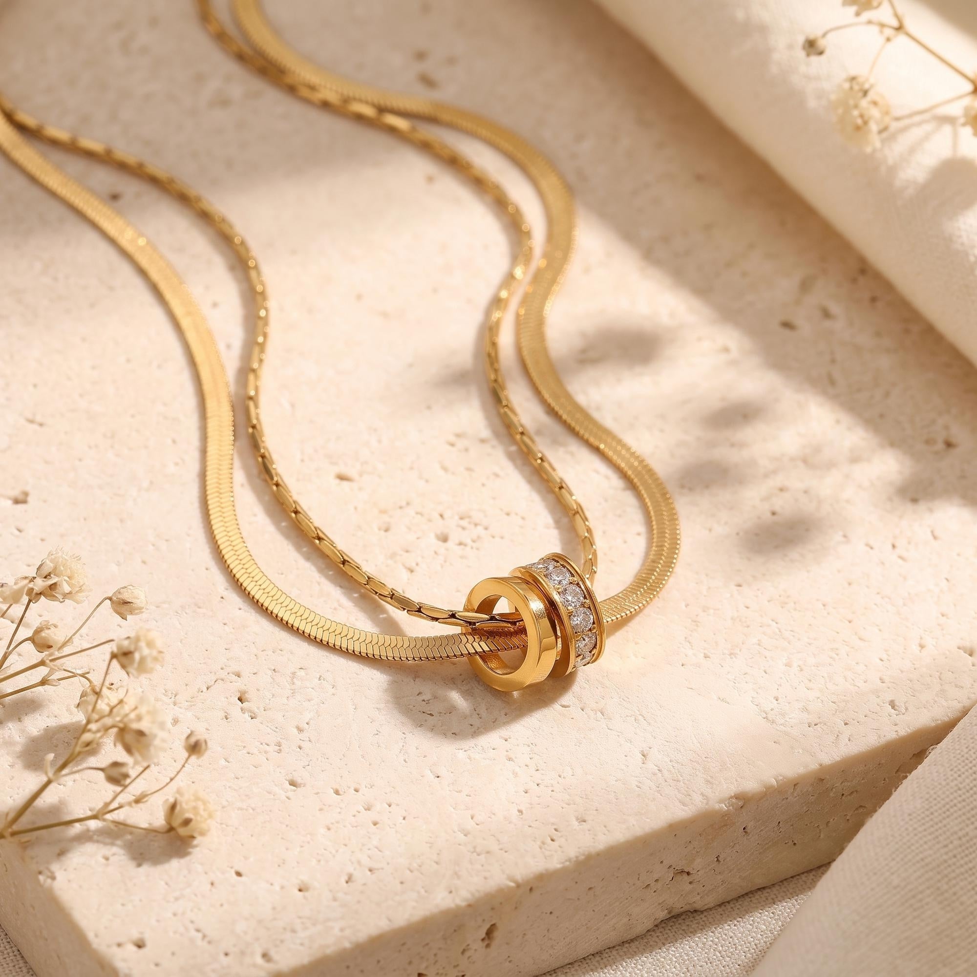 Macro view of gold interlocking rings and cubic zirconia on a stone background.