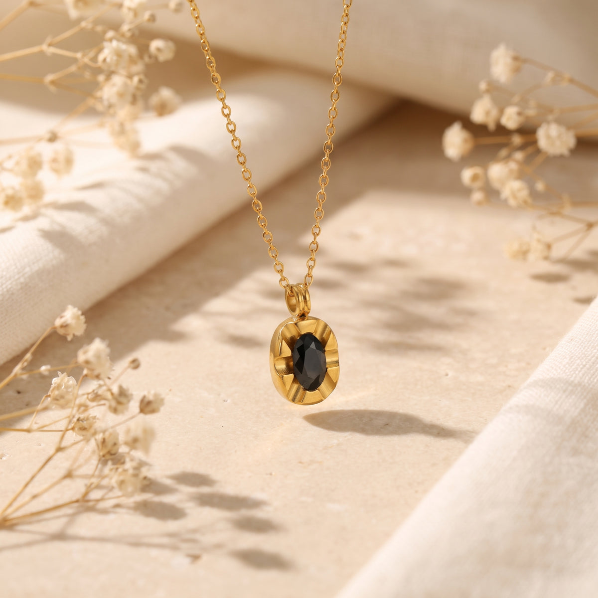 Suspended view of the fluted gold oval medallion pendant with a black oval cubic zirconia center.