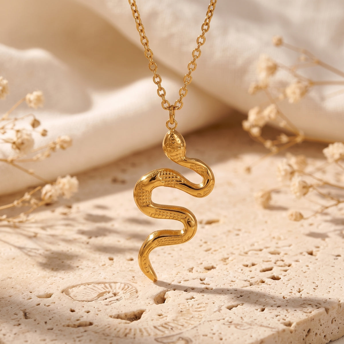 Detailed close-up view of the suspended gold-tone snake pendant showing textured scale patterns.