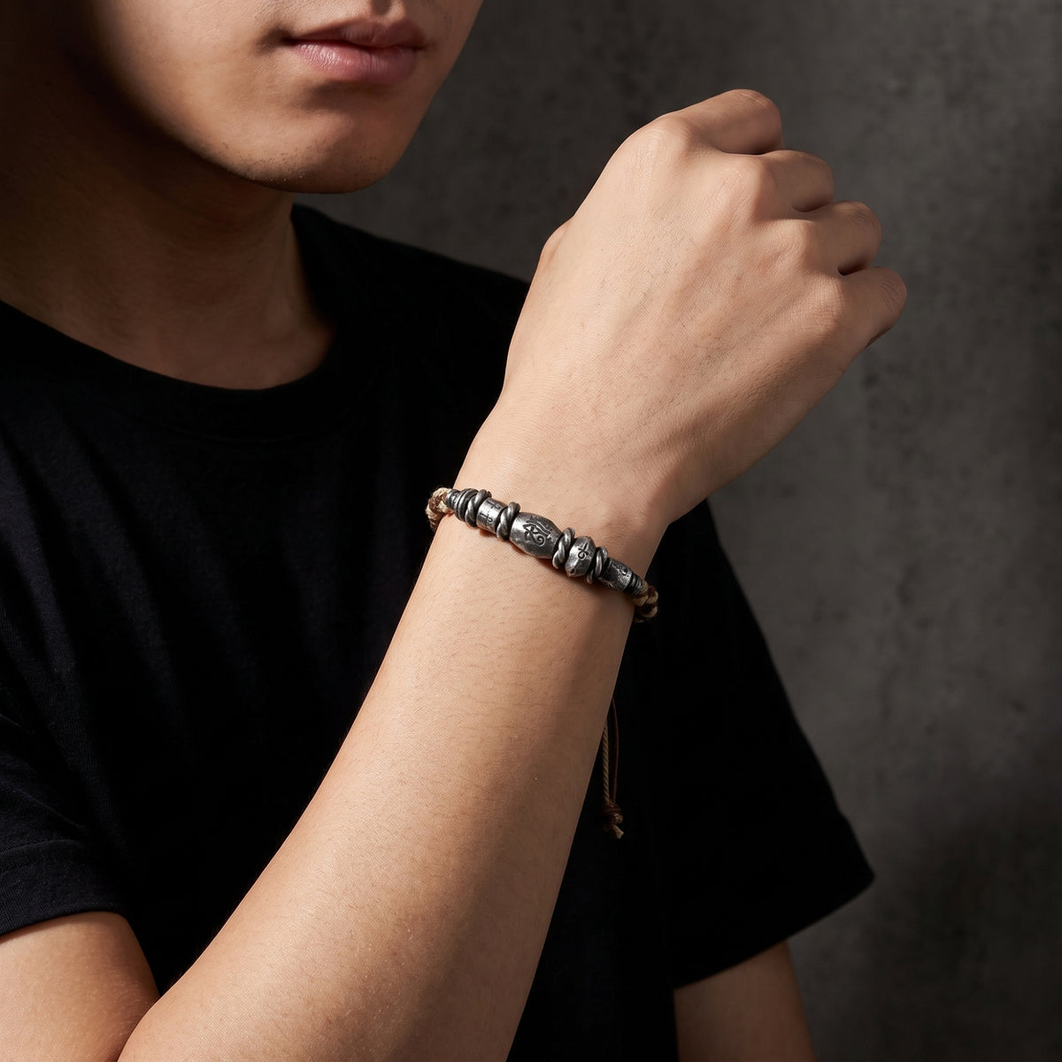 Model in a black T-shirt wearing the braided silver Eye of Horus bracelet on his wrist.
