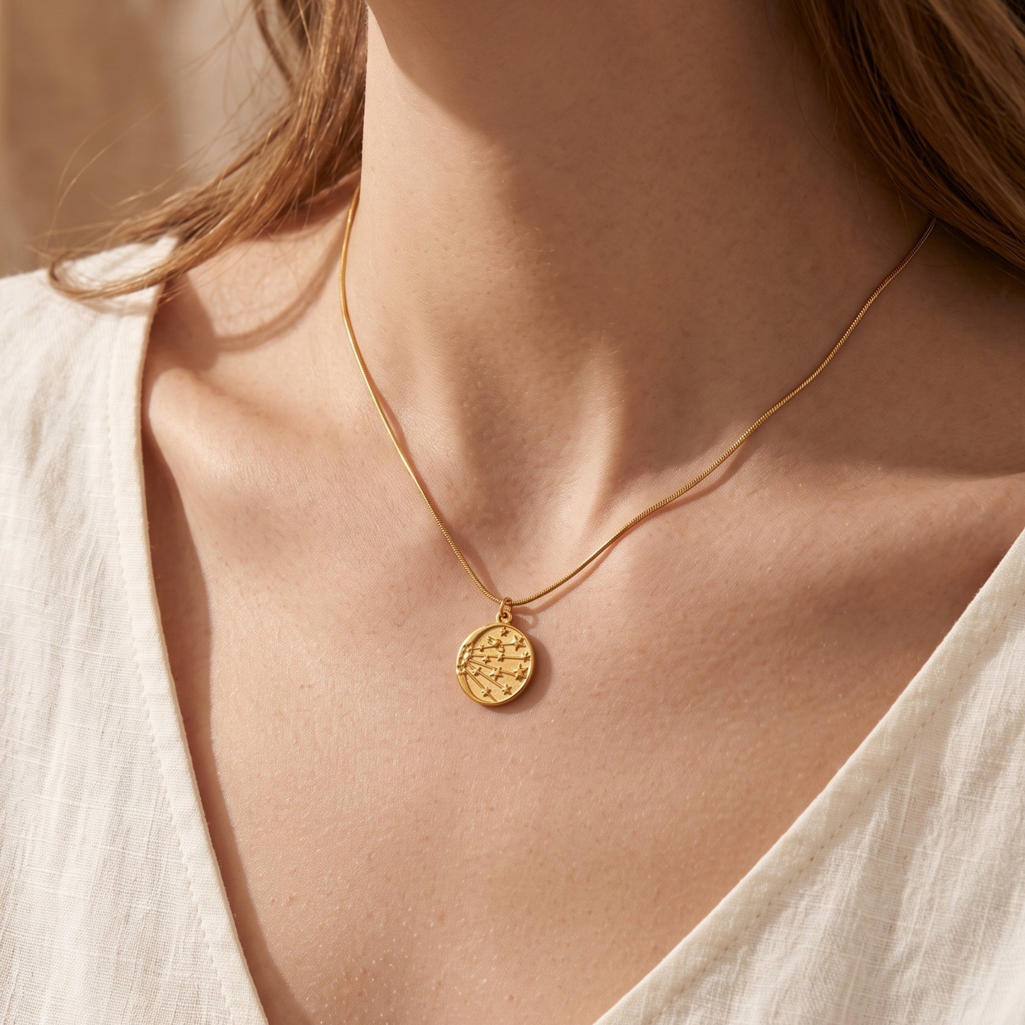 18K gold celestial medallion necklace worn by a model in a white top.