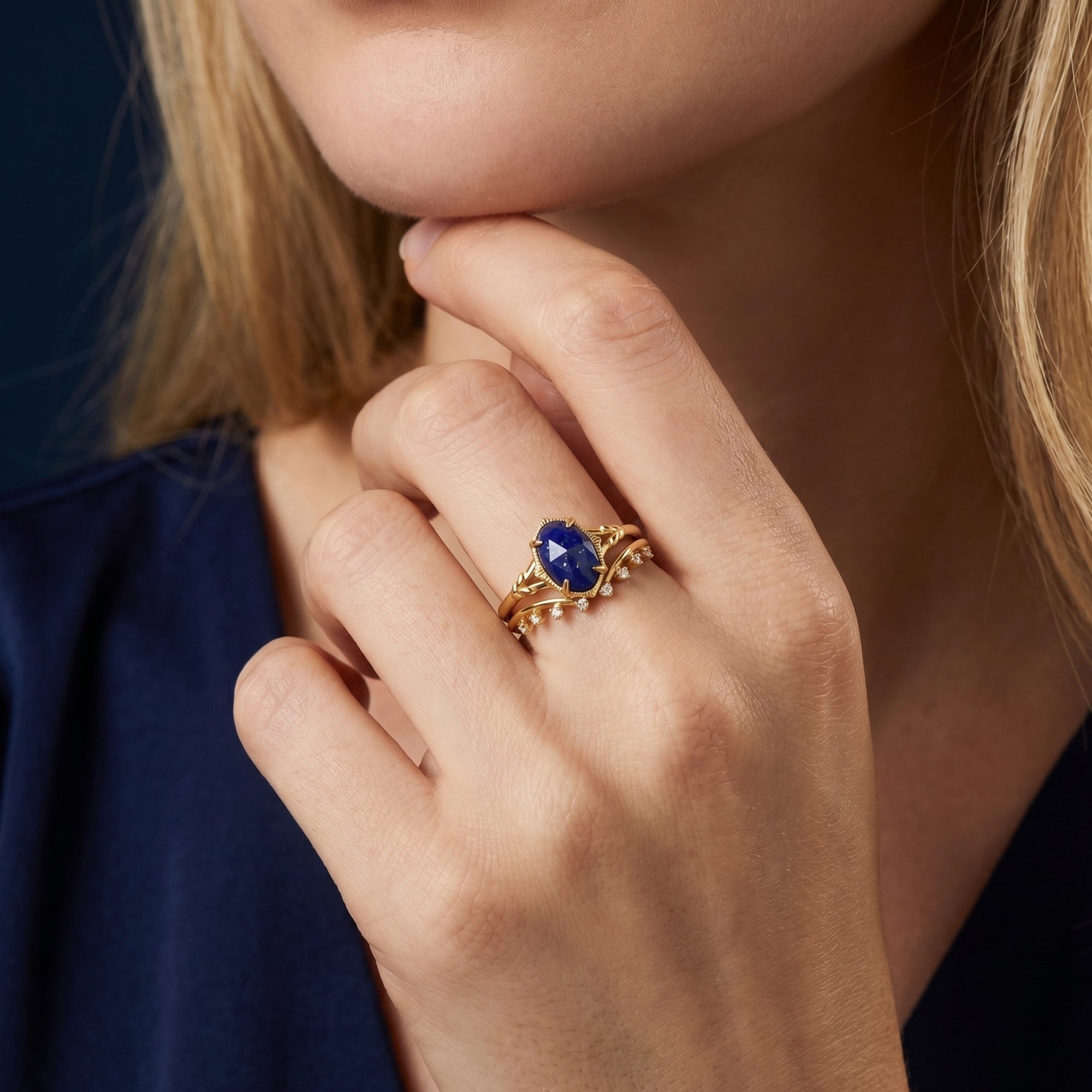 Close-up of a woman's hand wearing the gold plated oval lapis ring set against a blue garment.