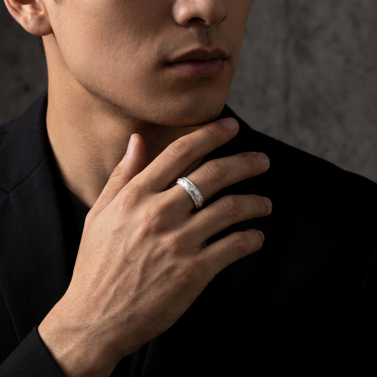 Close-up of a model wearing the etched silver open band ring with his hand held beneath his chin.