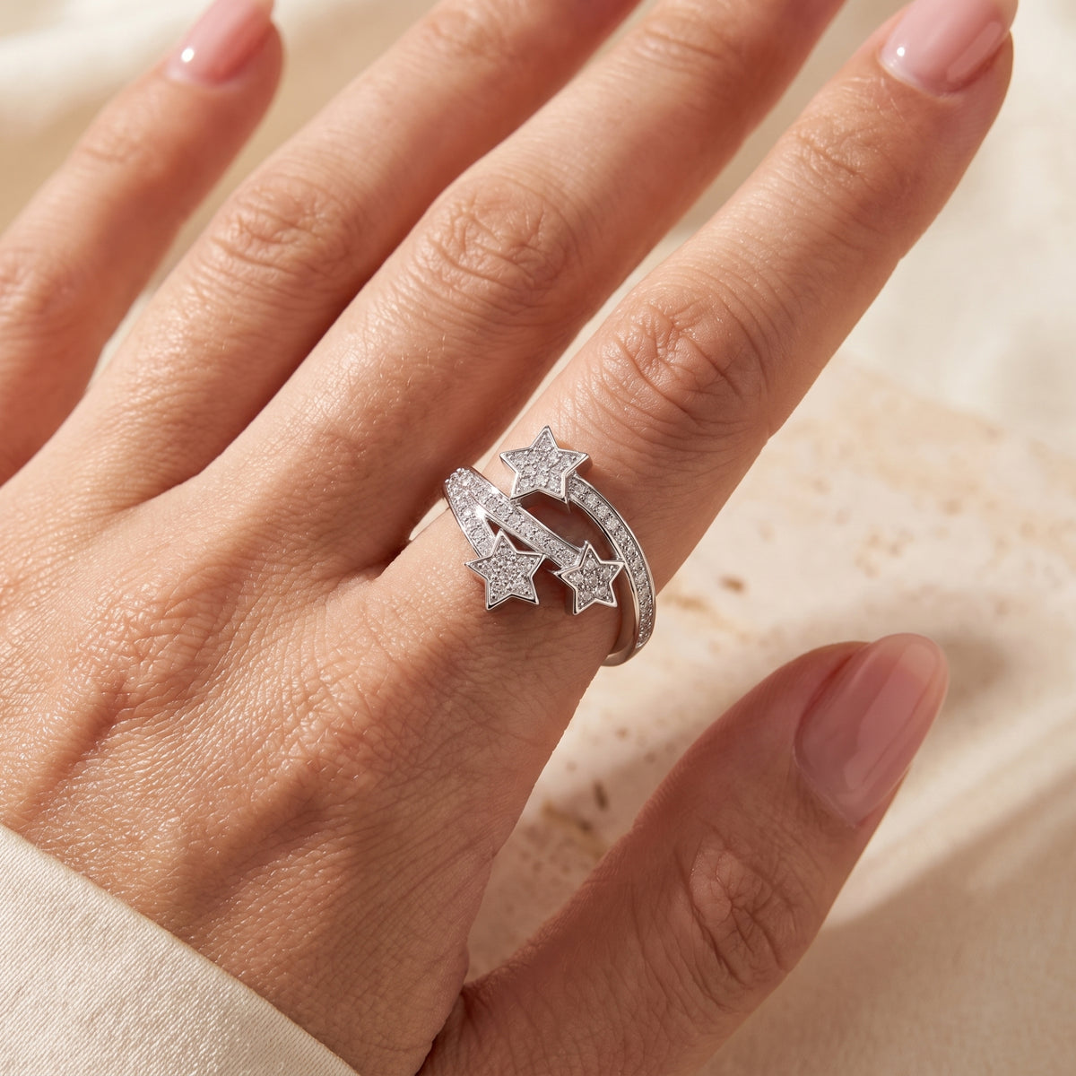 Close-up of the silver triple-star bypass ring worn on a hand, highlighting its pave details.