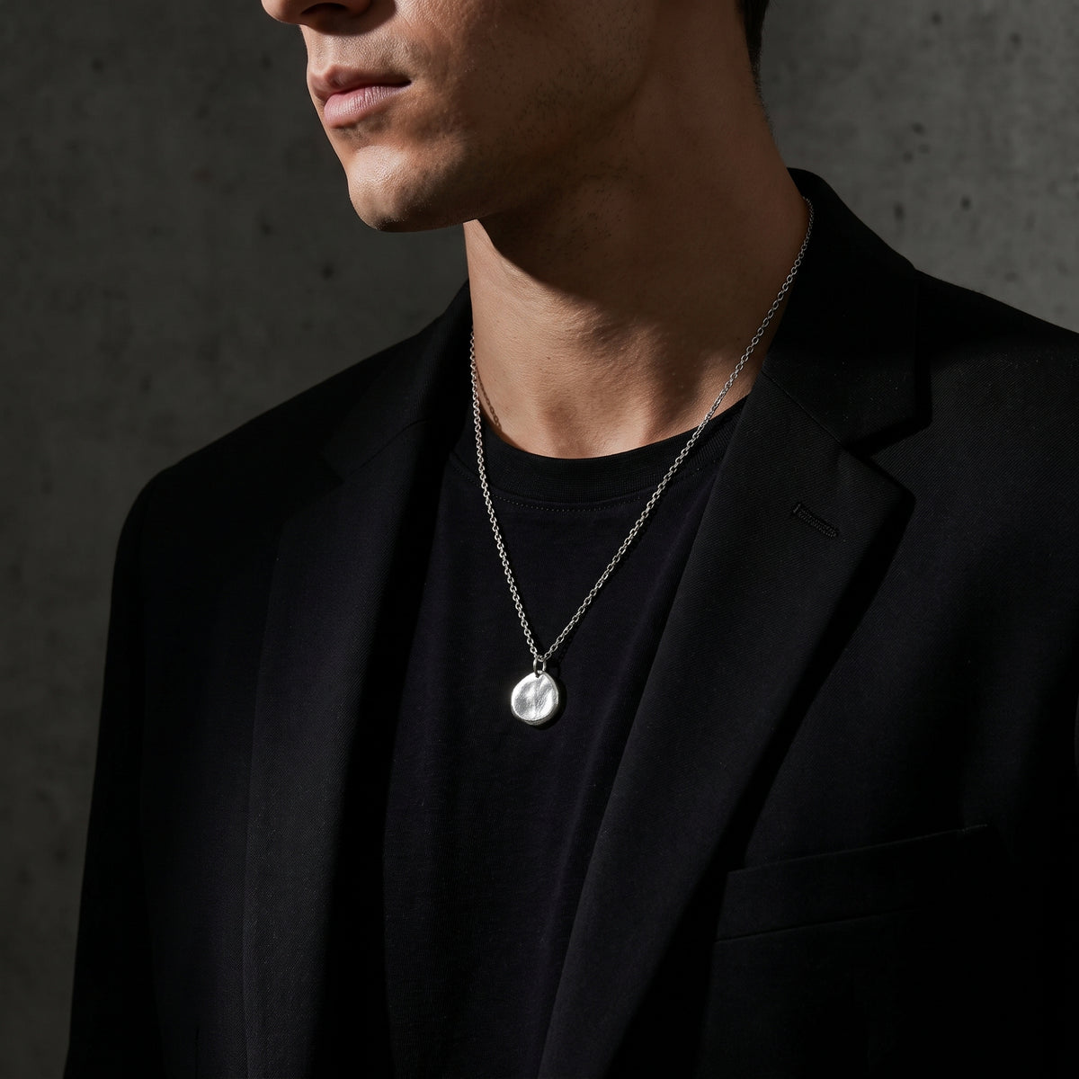 Model wearing the silver pebble pendant necklace with a black T-shirt and blazer.