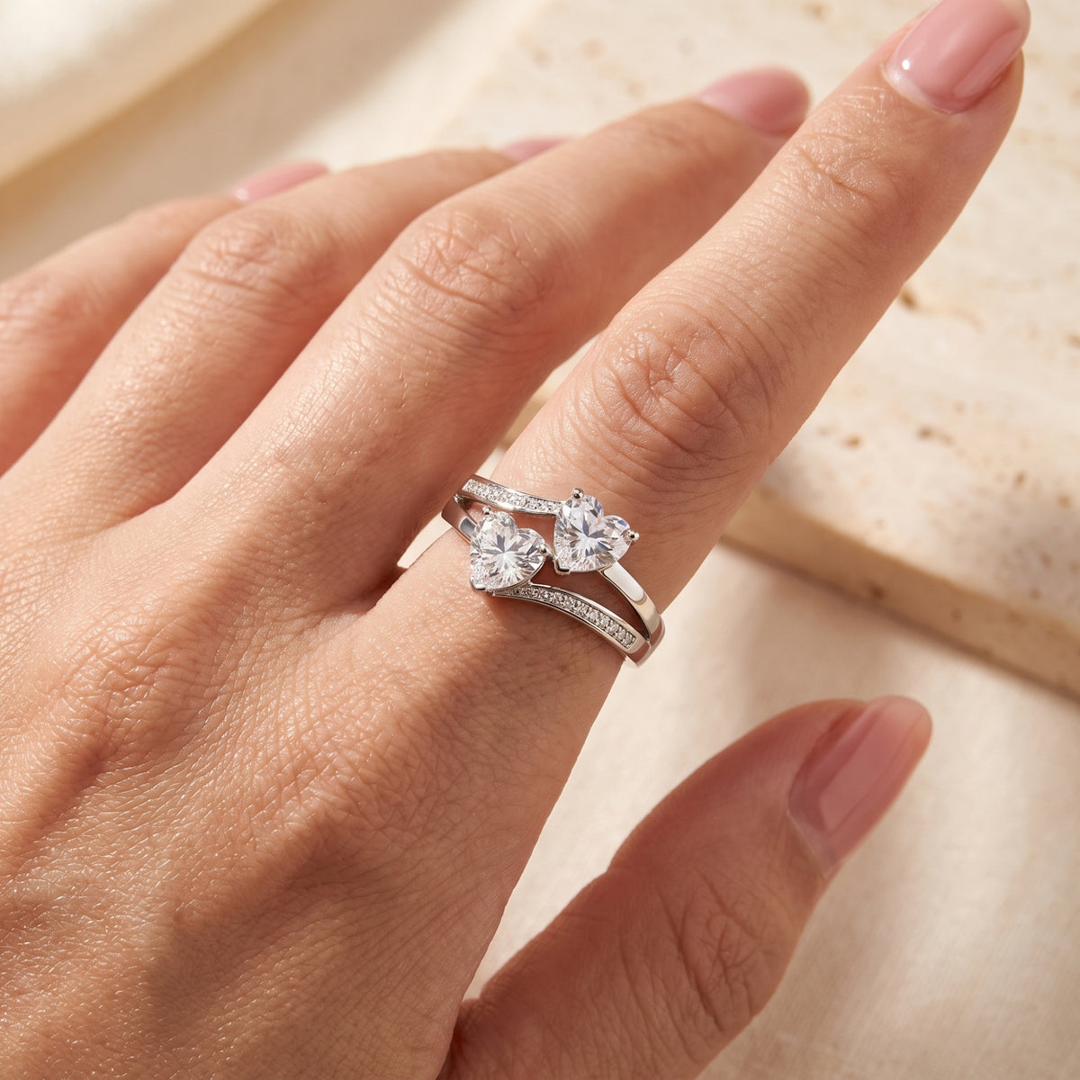 Close-up of the silver twin heart bypass ring with pavé accents worn on a hand.