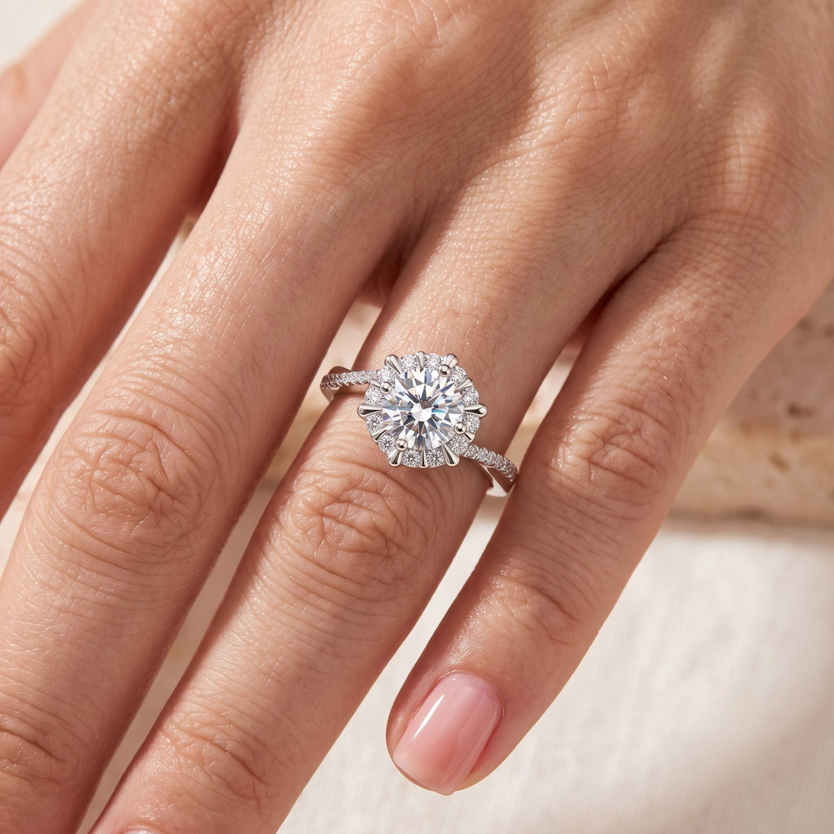 Top view of the silver sunburst halo ring worn on a hand, highlighting the round center stone.