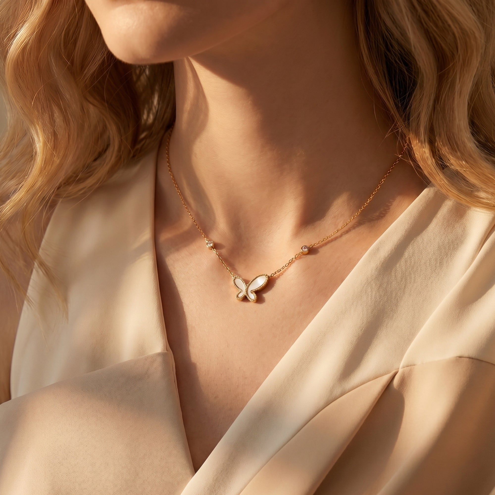 Model wearing a gold mother of pearl butterfly necklace in warm lighting.