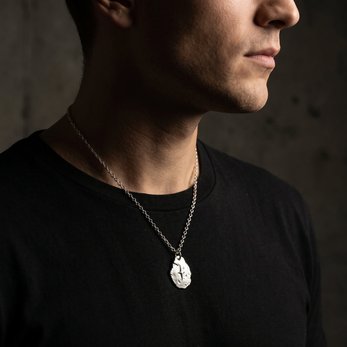 Side-profile view of a man wearing the silver starburst pendant necklace.
