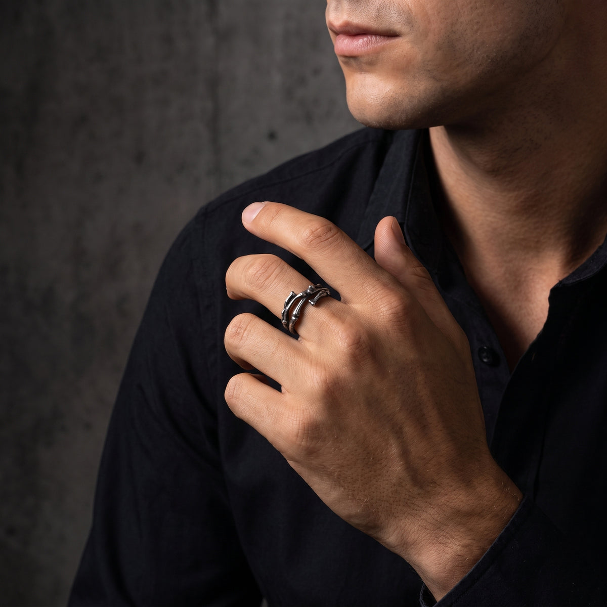 Model wearing the silver skeletal open band ring on his middle finger against a dark shirt.
