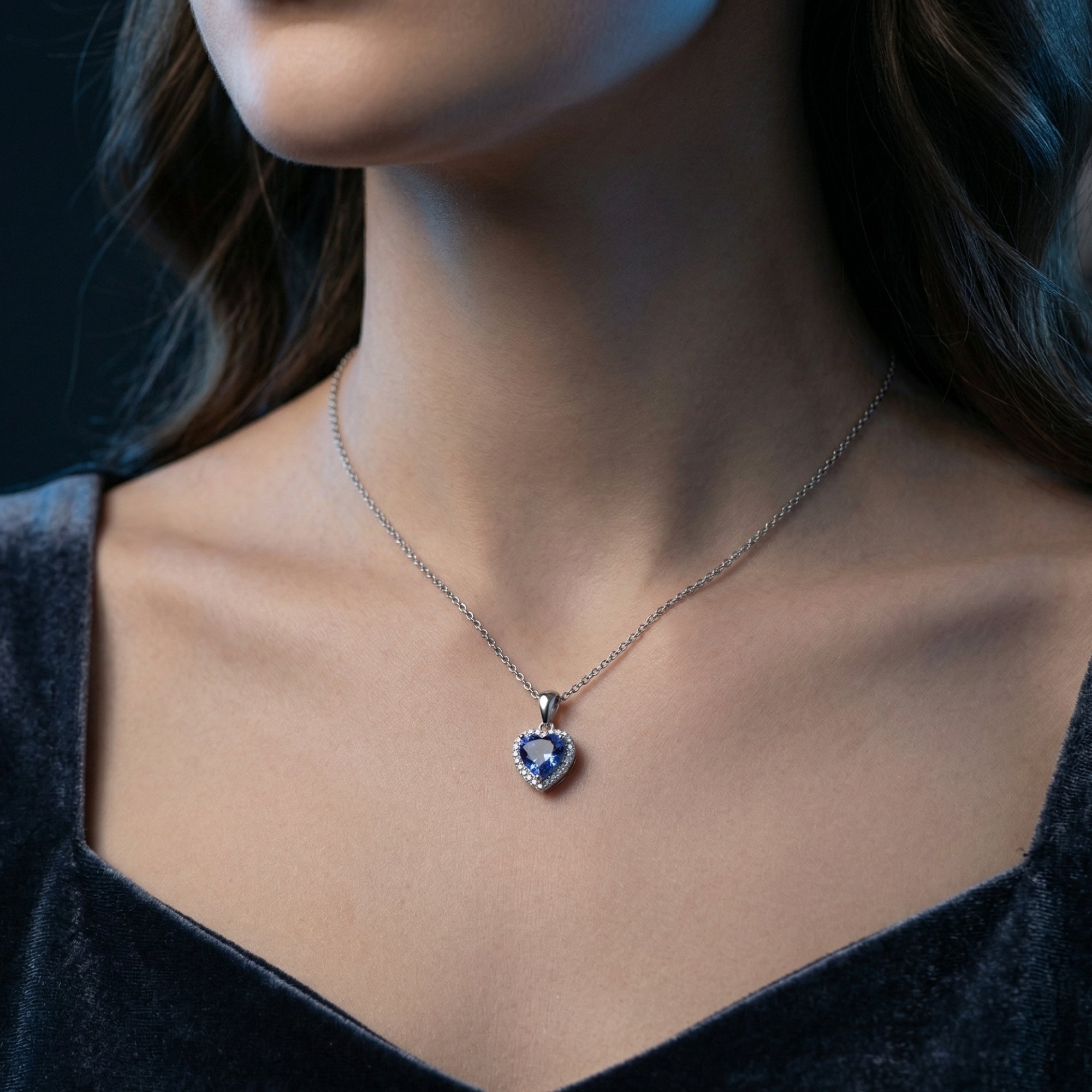 Front view of a model wearing the Emmeline heart-cut tanzanite necklace in sterling silver against a dark dress.