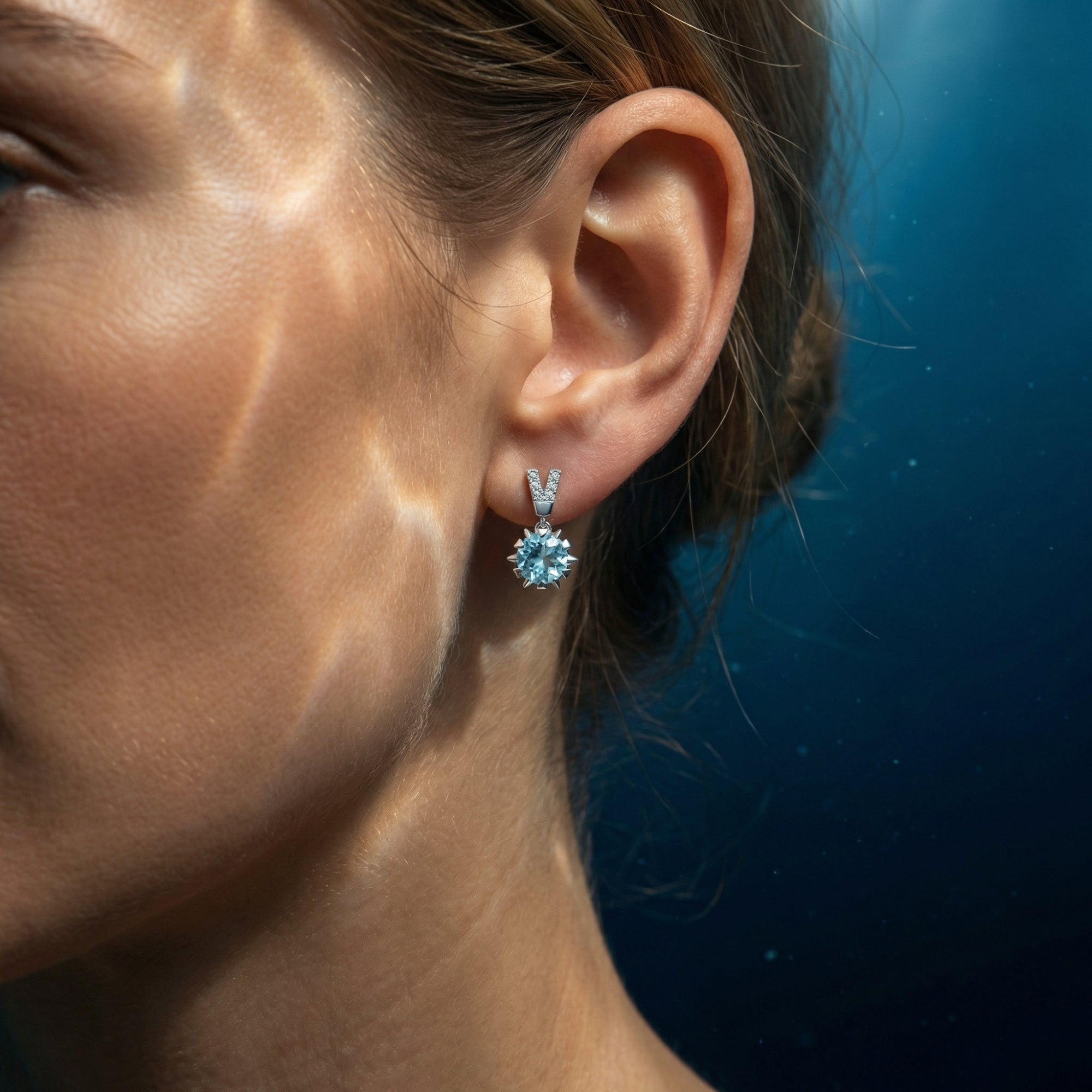 Side view of a model wearing the Nerea platinum drop earrings featuring round cut natural aquamarine stones.