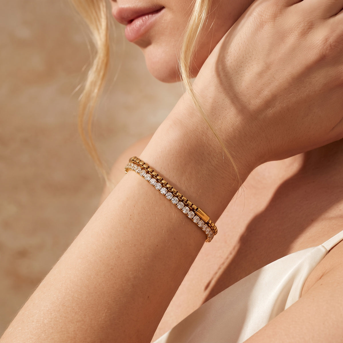 Side profile of a model wearing the gold-tone layered bracelet with cubic zirconia stones on her wrist.